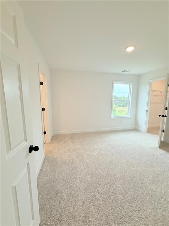 Bright bedroom with neutral carpet and walk-in closet in The Hickory B floor plan at Wehunt Meadows, Hoschton, Georgia.
