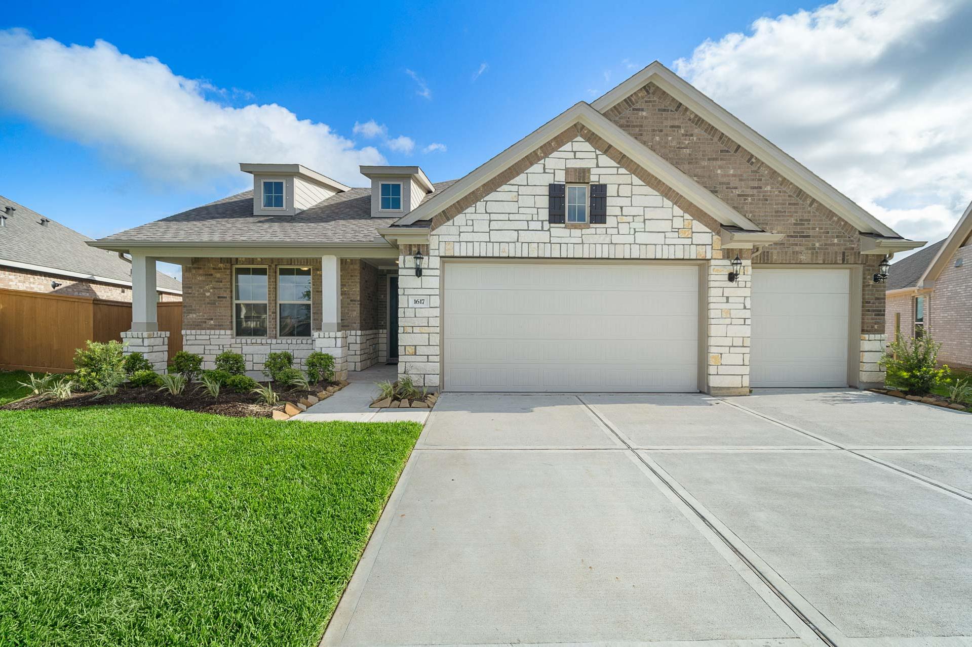 Modern stone and brick home exterior at Sierra Vista in Rosharon TX with covered porch and two-car garage