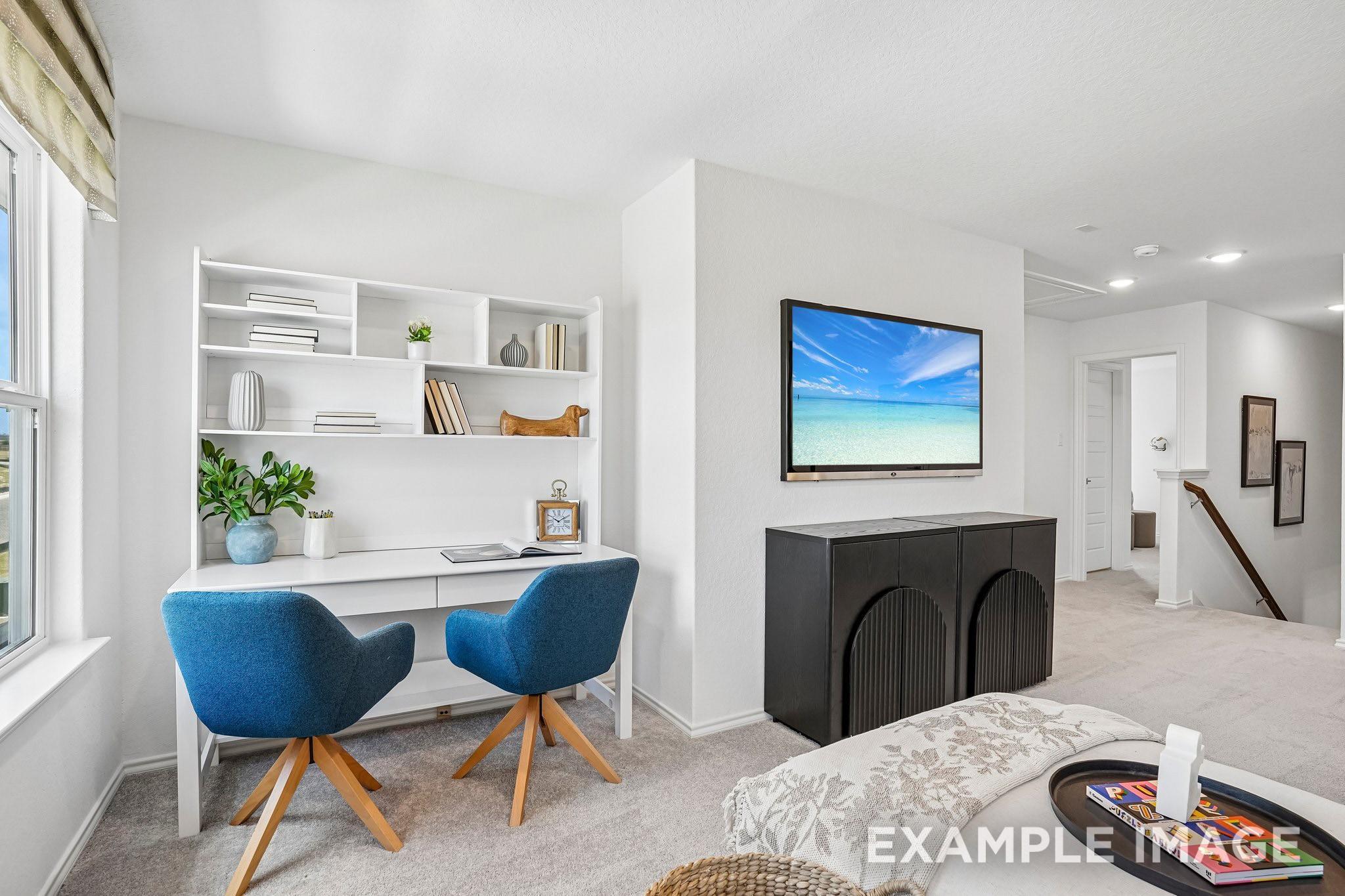 Bright primary bedroom with built-in desk, wall-mounted TV, and cozy seating in Davidson Homes' The Ashport J, Sundance Cove, Crosby, TX