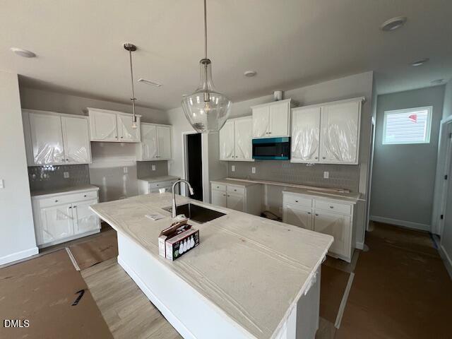 Modern white shaker kitchen with oversized island sink, subway tile backsplash, and pendant lights in The Adalynn B, Lillington, NC
