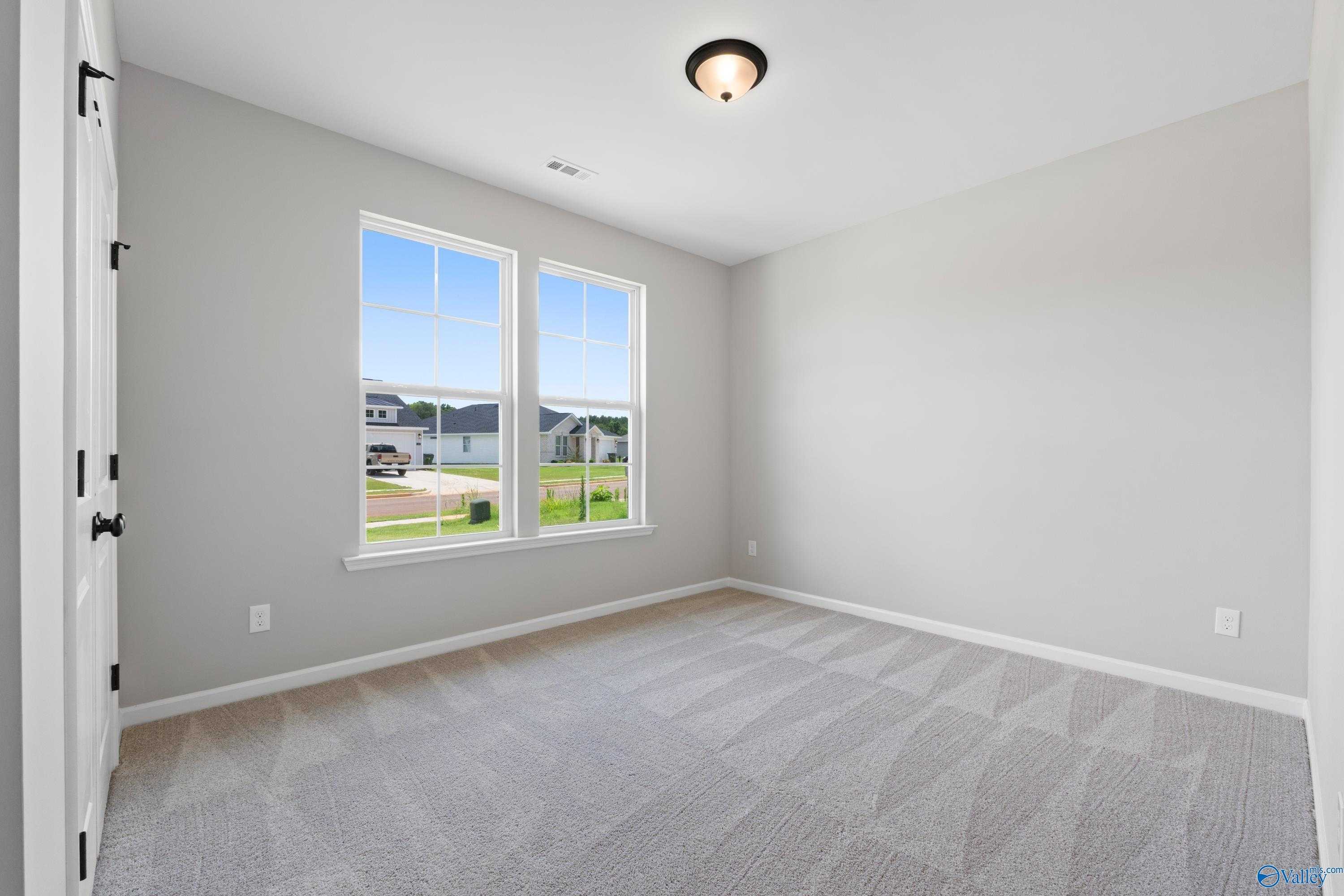 Bright secondary bedroom with large windows overlooking green yard in Davidson Homes The Phoenix, Hazel Green, Alabama