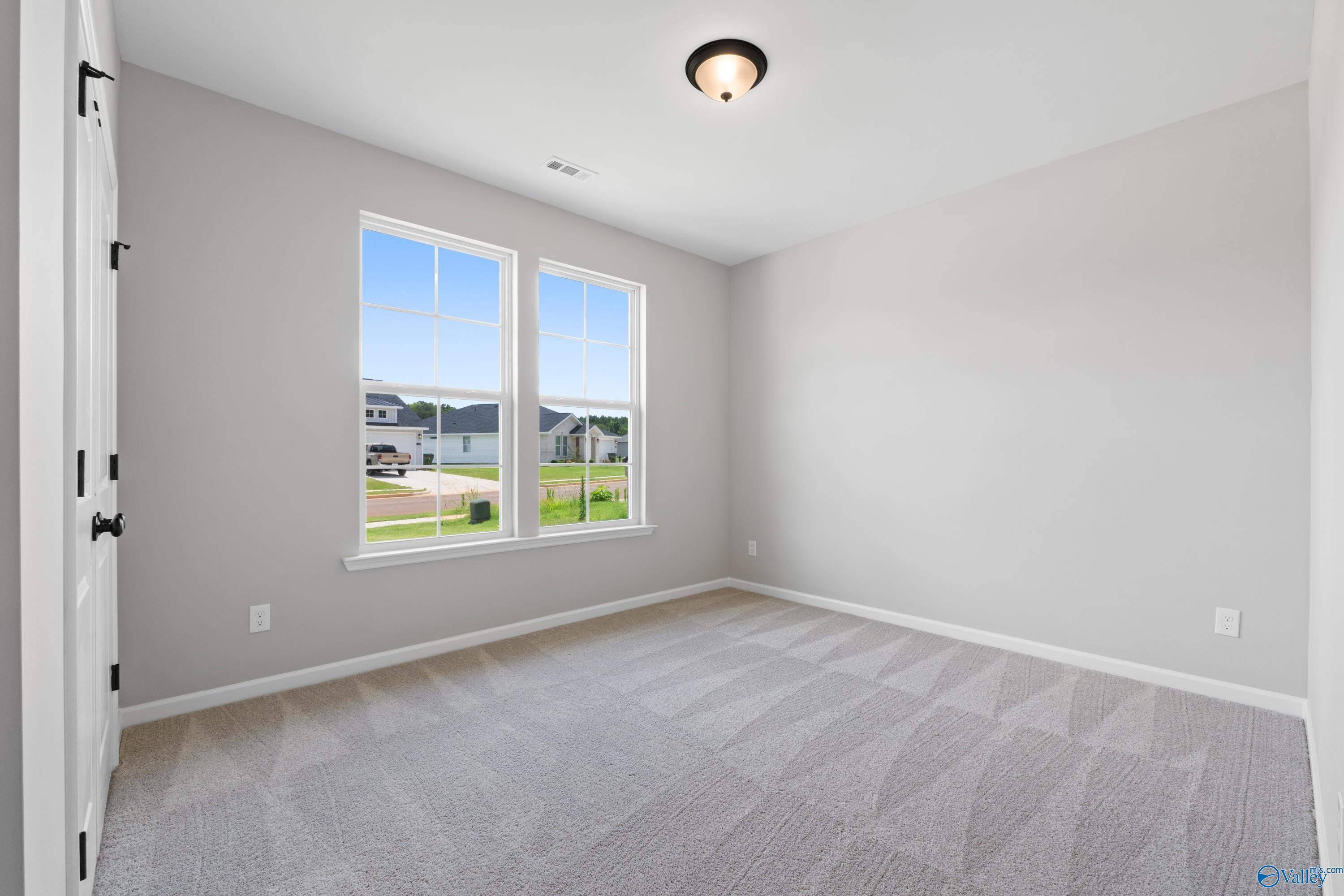Bright secondary bedroom with large windows, gray walls, and carpet in Davidson Homes The Phoenix, Hazel Green, Alabama
