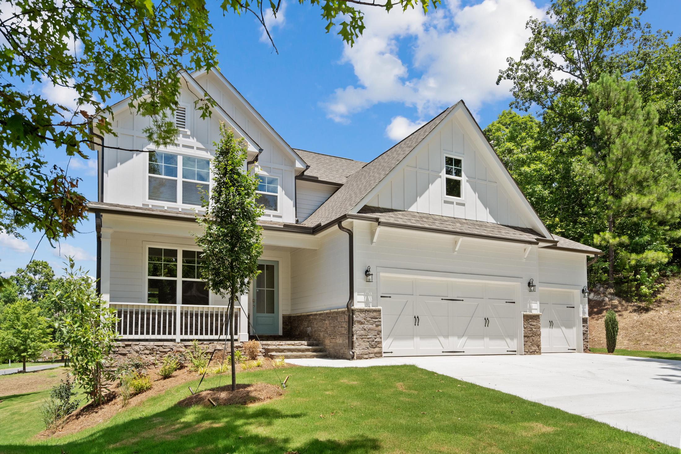Modern farmhouse home exterior at Mountainbrook in Cartersville, Georgia with covered porch, two-car garage and lush landscaping