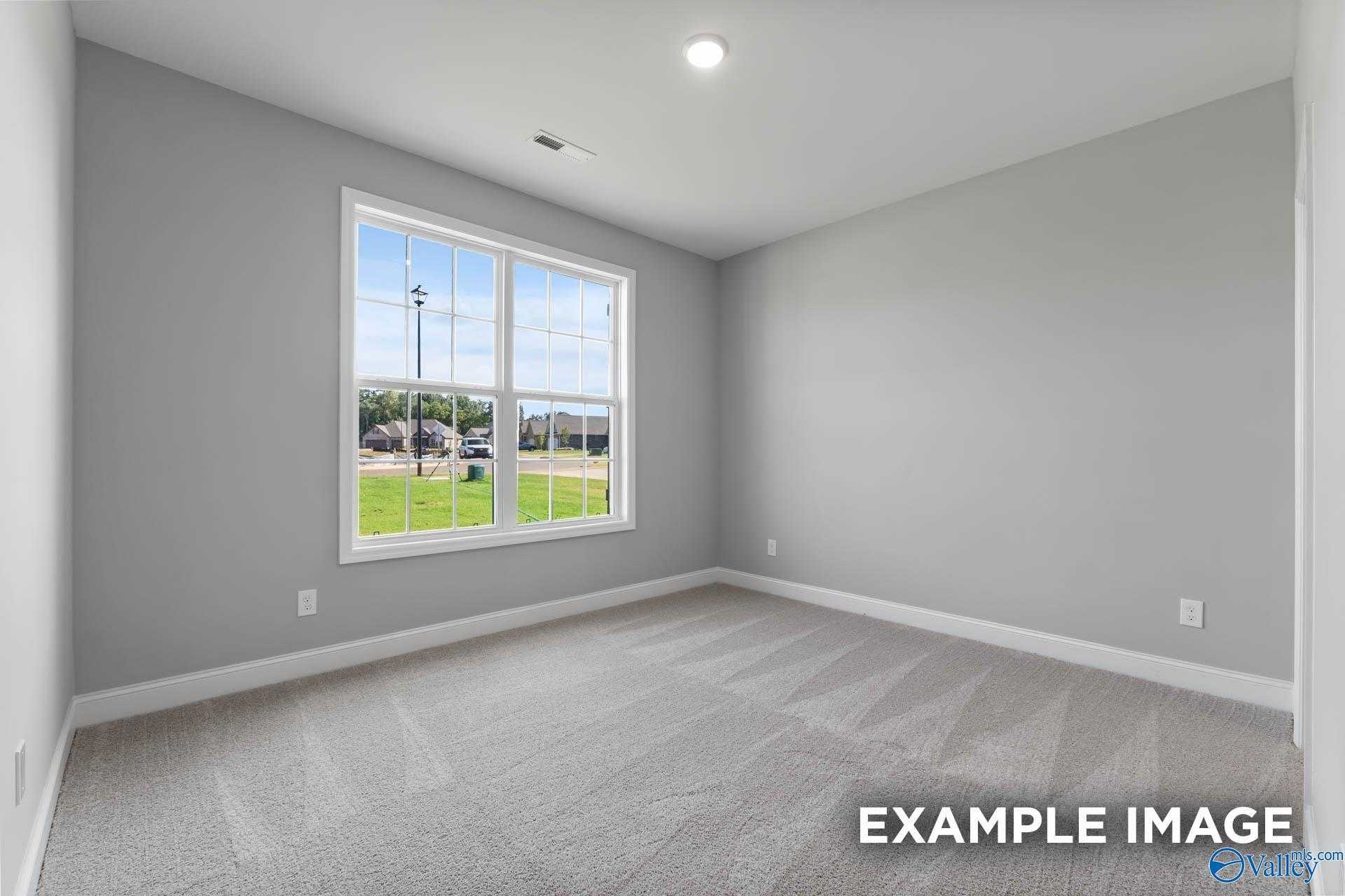 Bright secondary bedroom with gray walls, carpet floor, and large window overlooking green field in Davidson Homes The Rockford D, Hazel Green, Alabama