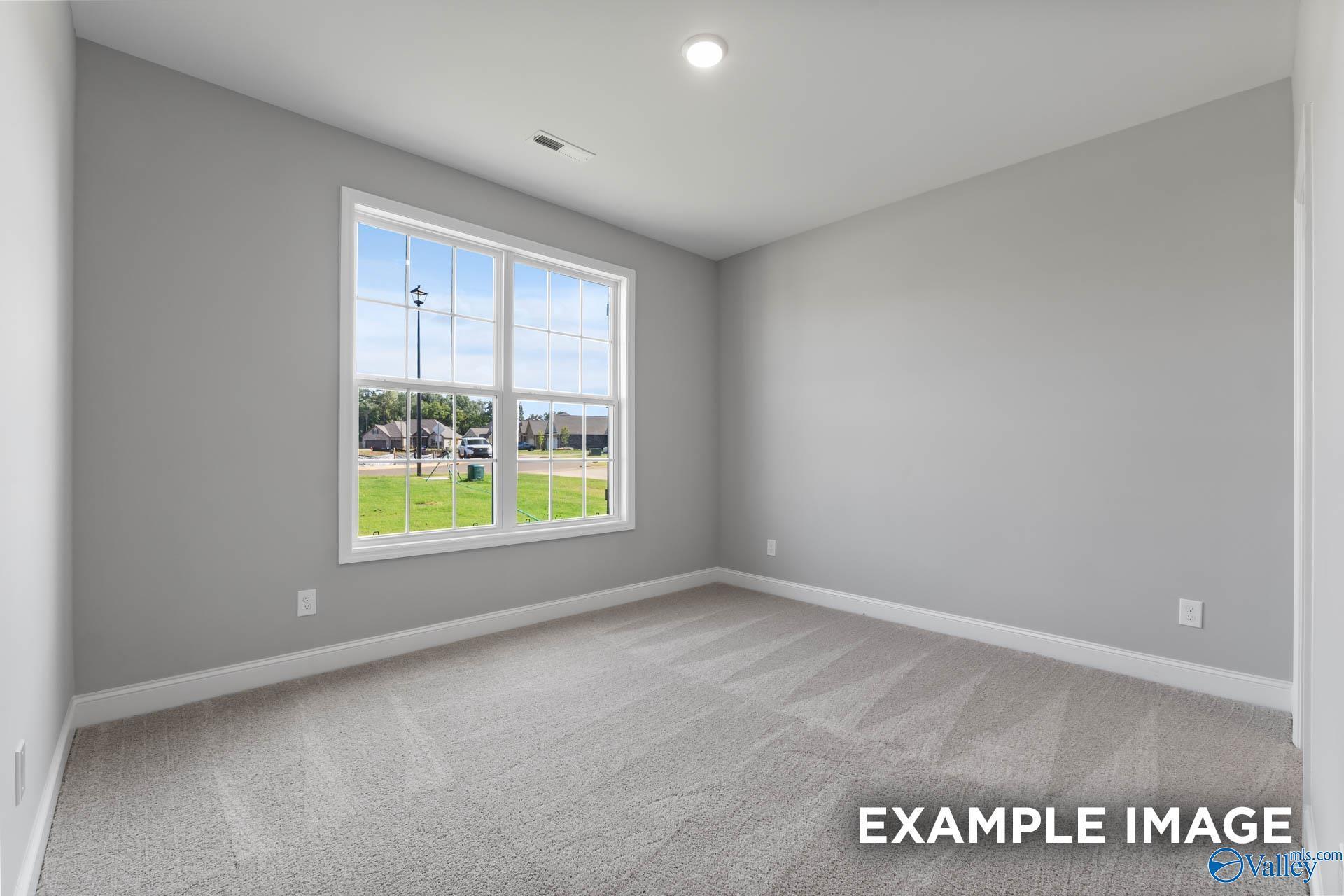 Bright empty bedroom with gray walls, carpet floor and large window to green field in Davidson Homes The Rockford with Bonus, Madison, Alabama