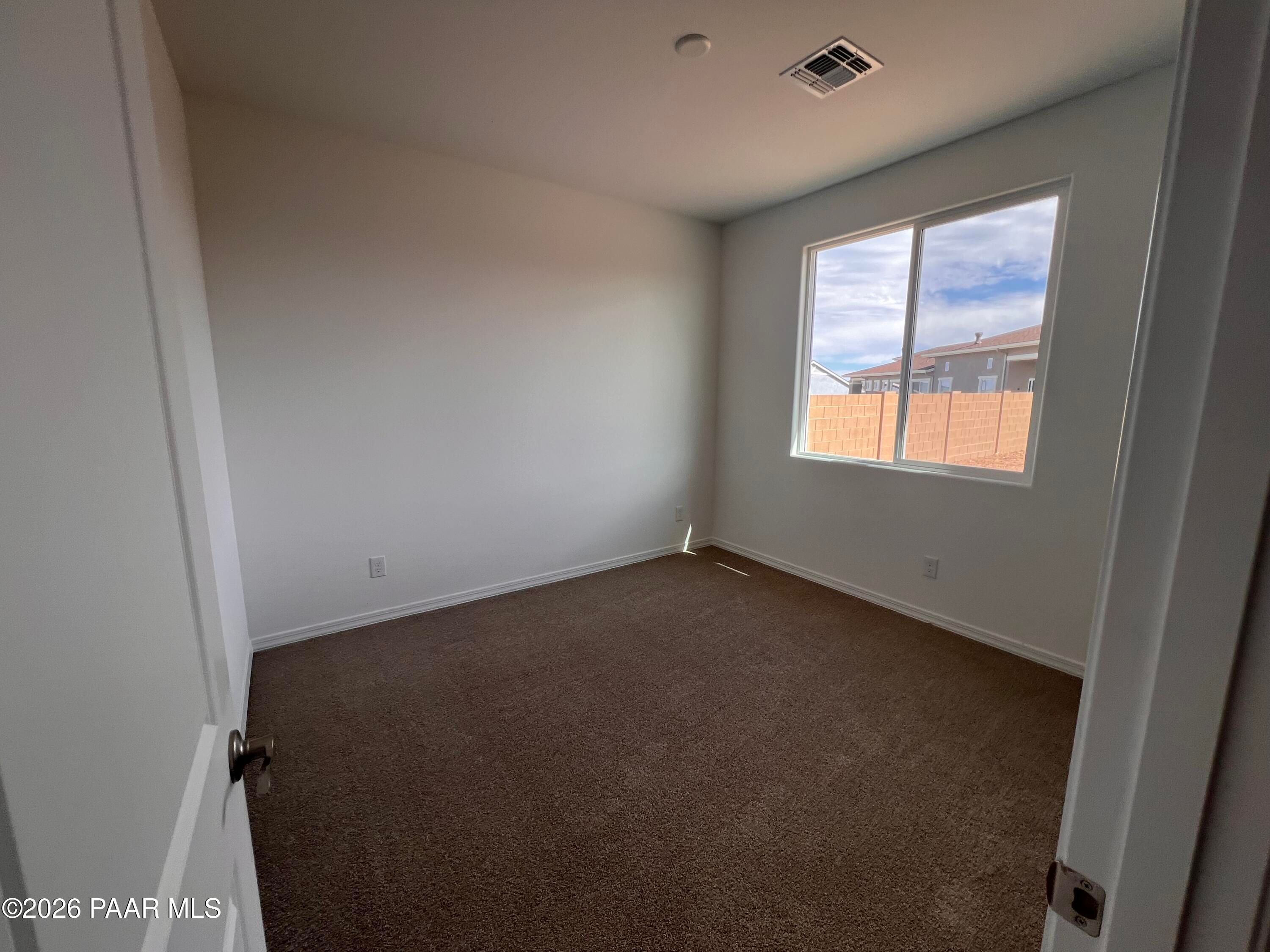Empty bedroom with beige carpet, large window overlooking Prescott skyline in Davidson Homes The Monarch A, Arizona