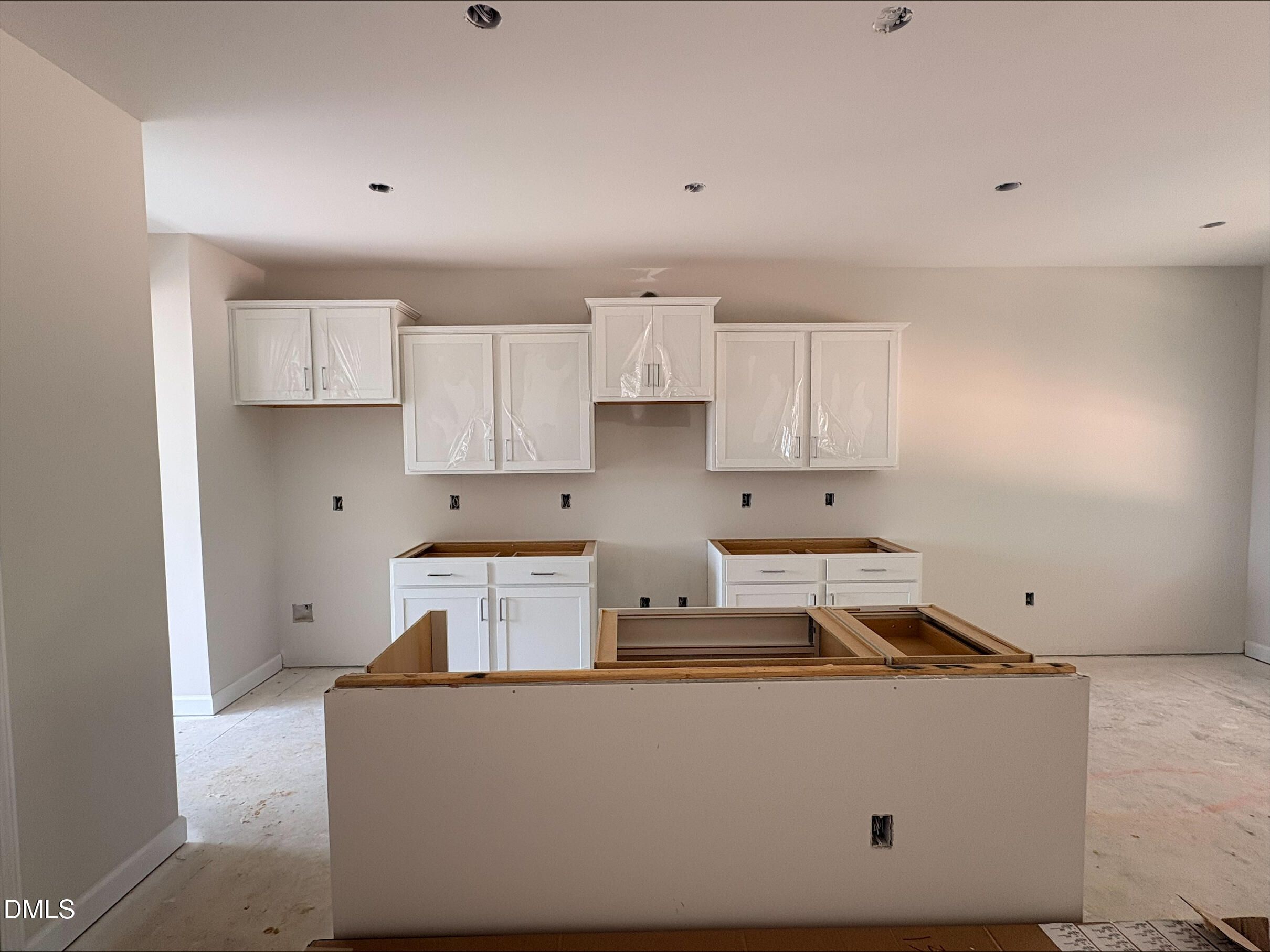 White kitchen cabinets and center island under construction in The Willow C floor plan at Woodland Crossing, Zebulon, NC.