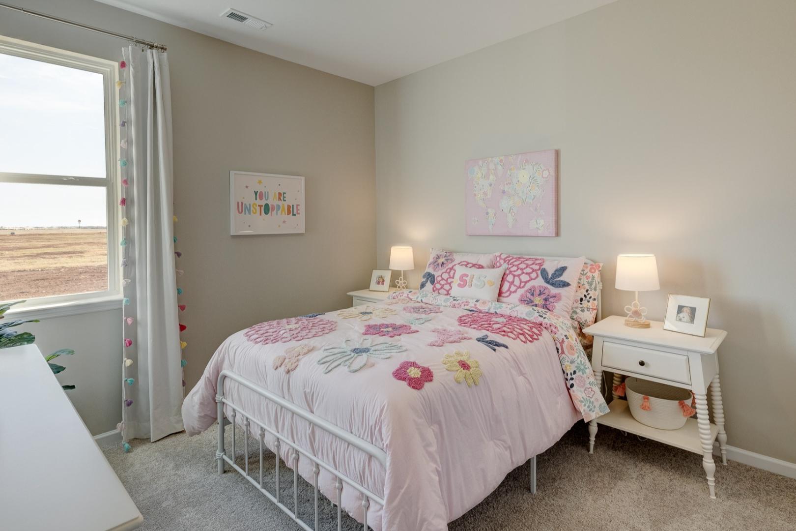 Charming girl's bedroom in Aurora A by Davidson Homes featuring pink floral bedding, white nightstands, and sunny window decor