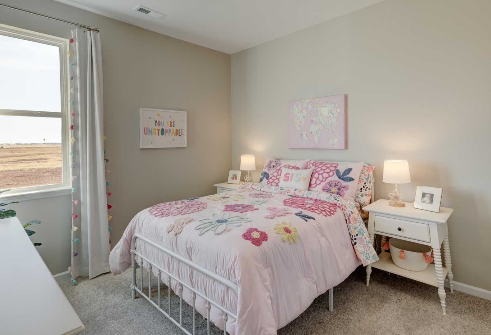 Charming girl's bedroom in Aurora A by Davidson Homes featuring pink floral bedding, white nightstands, and sunny window decor