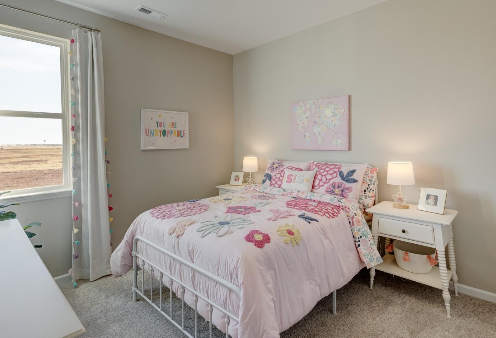 Charming girl's bedroom in Aurora A by Davidson Homes featuring pink floral bedding, white nightstands, and sunny window decor
