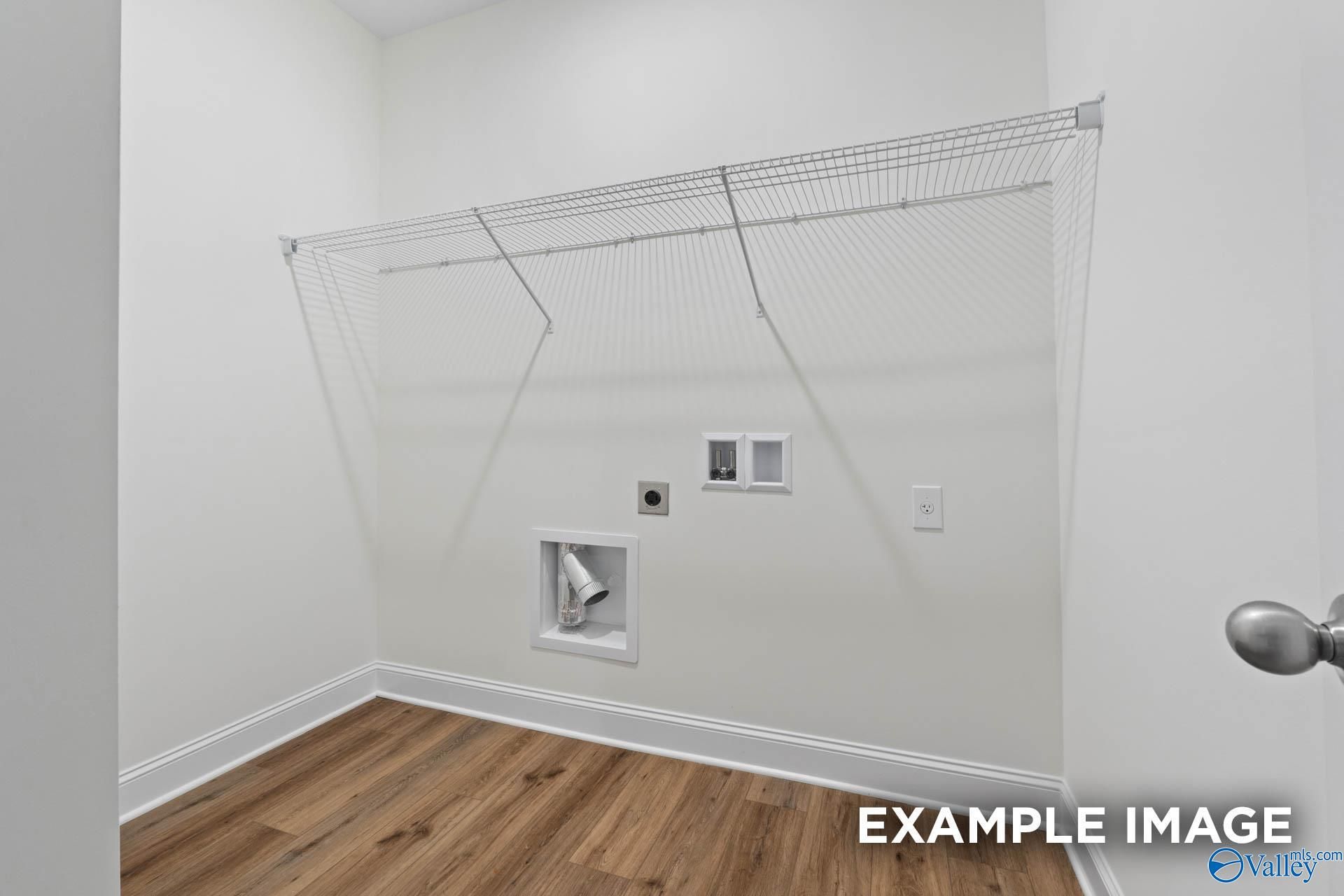 Spacious laundry room with wire shelving, washer/dryer hookups, and hardwood floors in Evermore Homes The Daphne E, Harvest, Alabama