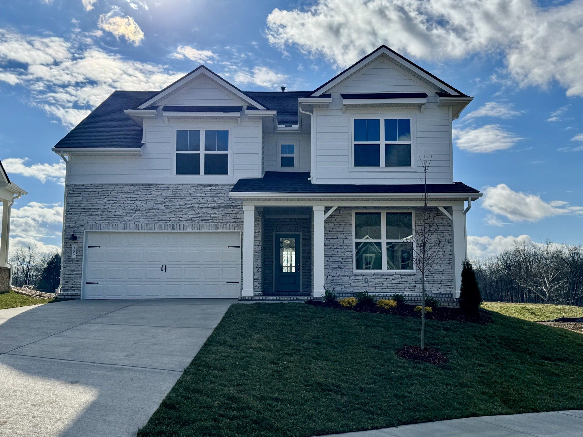 Modern two-story Ridgeport home by Davidson Homes in Woods Crossing, Gallatin, TN: gray brick exterior, 2-car garage, covered porch, lush lawn