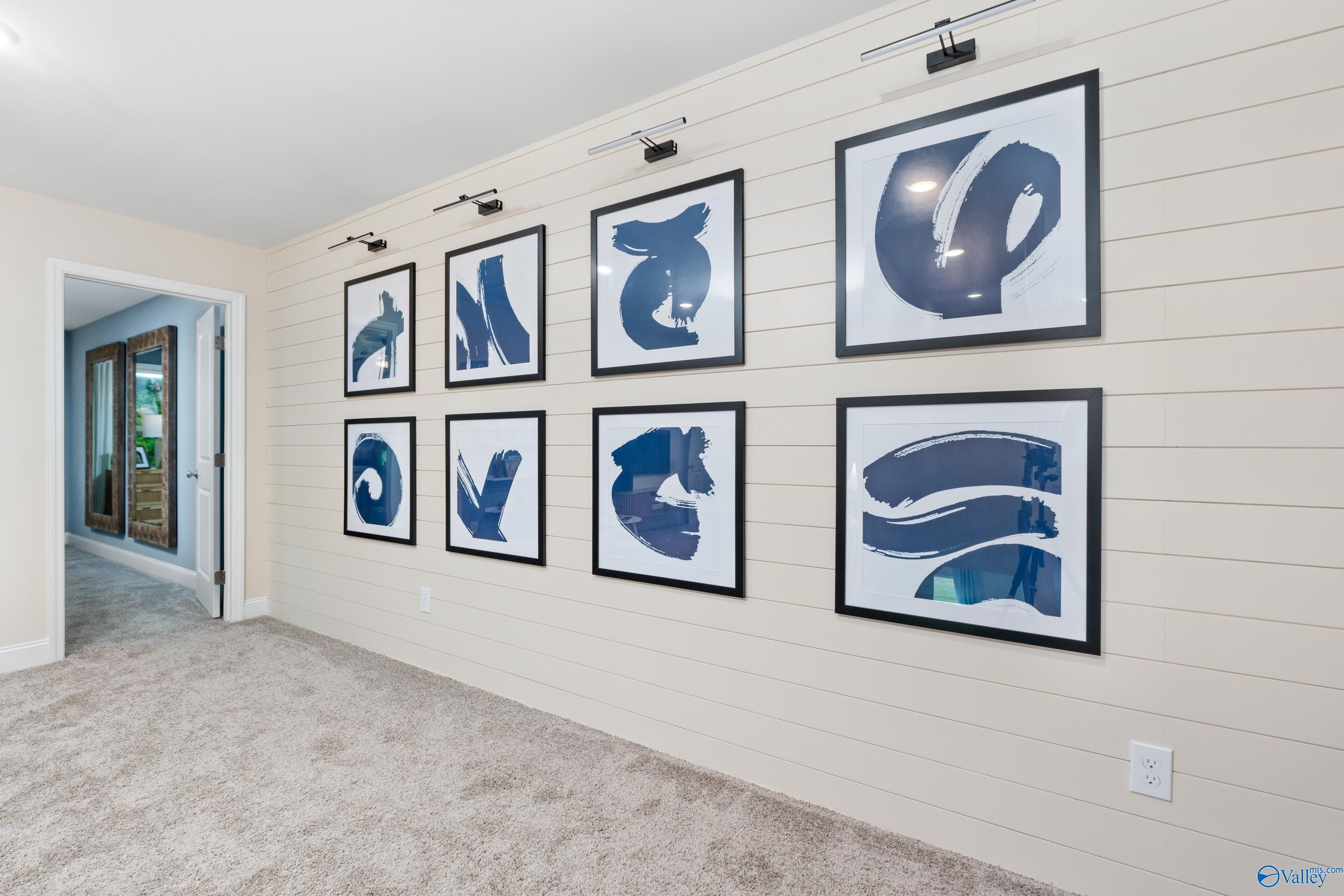 Elegant shiplap hallway with abstract blue framed artwork and wall sconces in Davidson Homes The Camden, Huntsville, Alabama