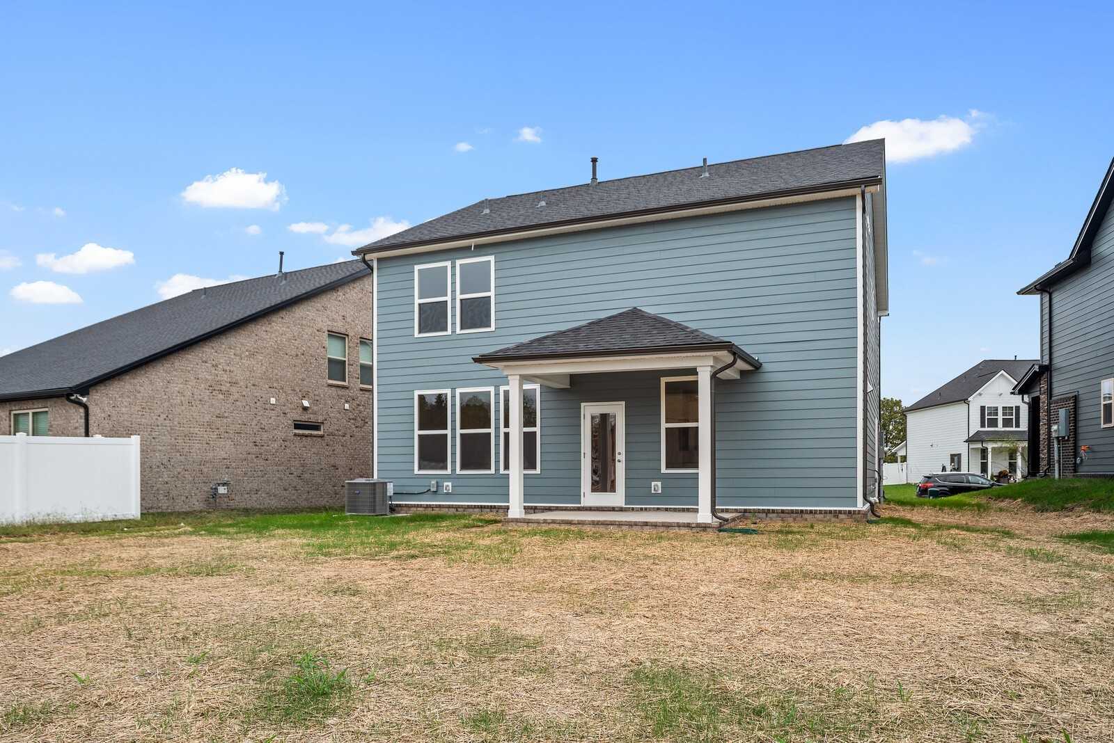 Two-story light blue home with 2-car garage, covered porch, and large windows in Woods Crossing, Gallatin, Tennessee