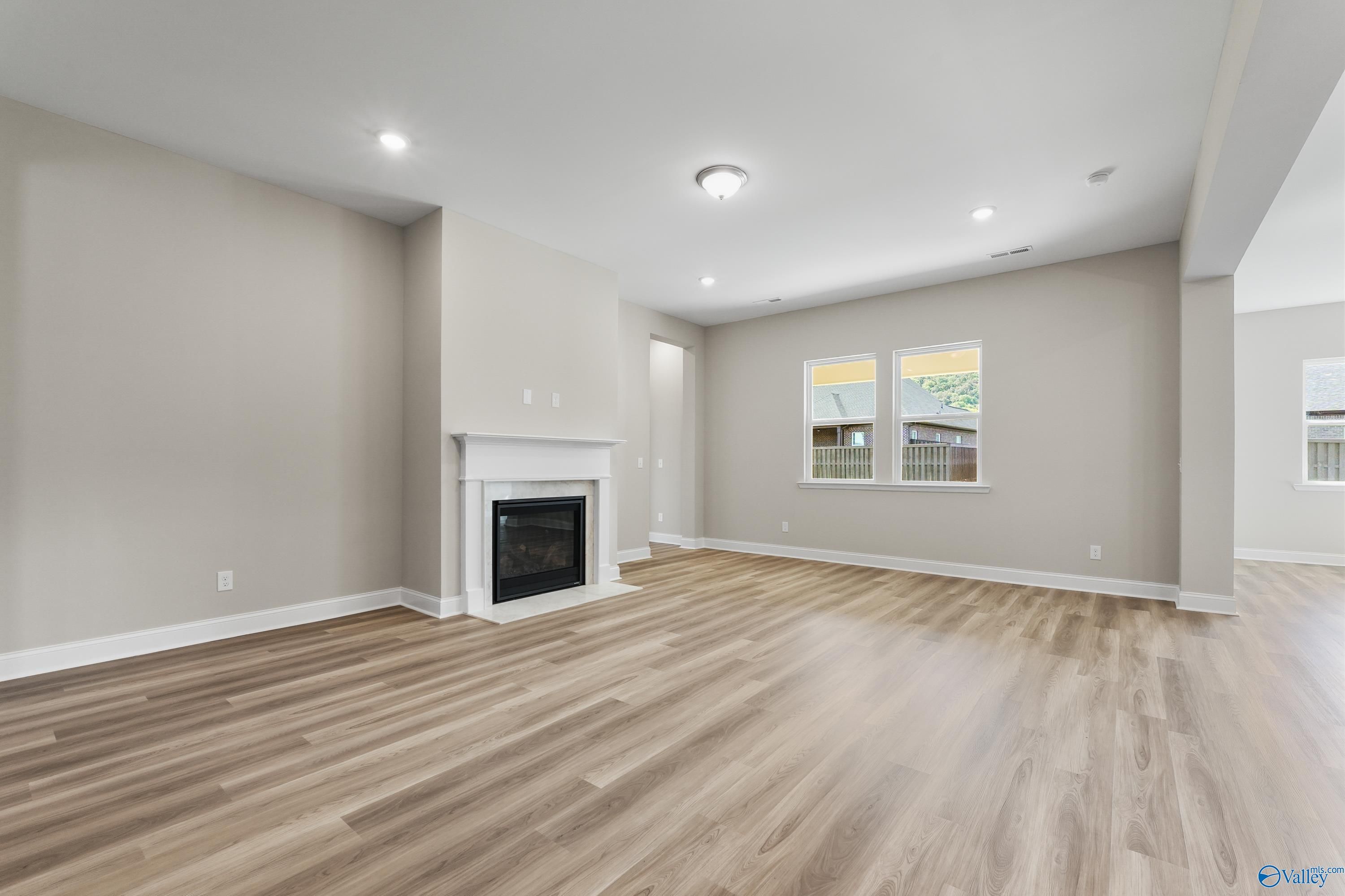 Cozy family room featuring white gas fireplace, hardwood floors, and neutral walls in Evermore Homes The Haven, Owens Cross Roads, Alabama