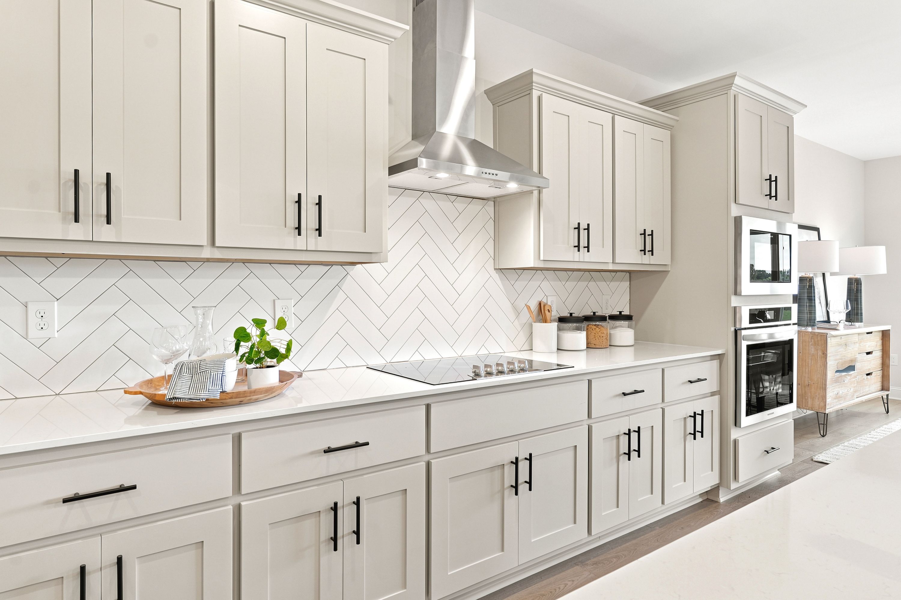 Modern kitchen at Riverton Preserve in Huntsville, AL with white shaker cabinets, quartz countertops, and herringbone backsplash