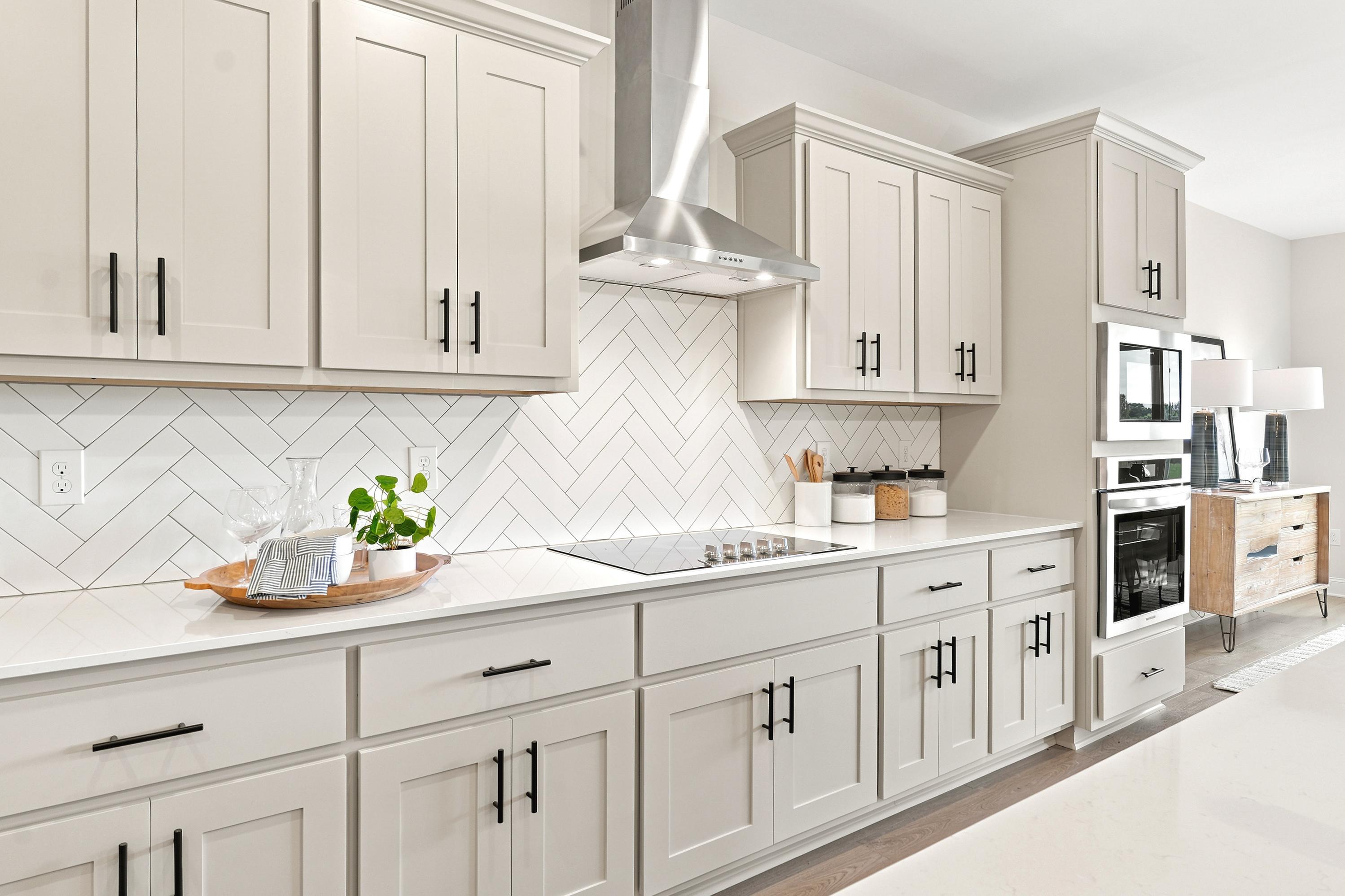 Modern kitchen at Riverton Preserve in Huntsville, AL with white shaker cabinets, quartz countertops, and herringbone backsplash