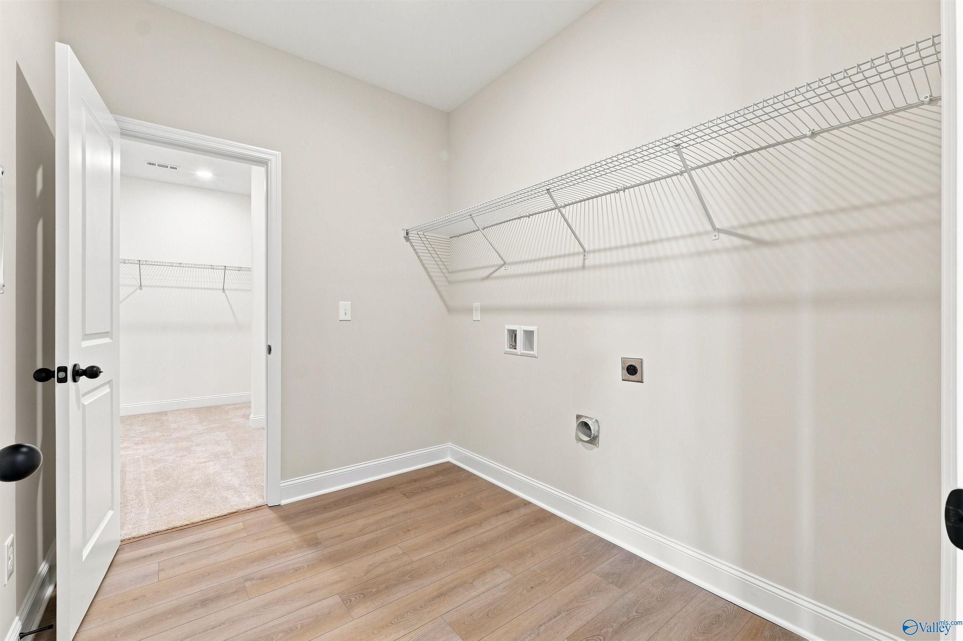 Laundry room with wire shelving, wood-look flooring, and dryer connections in Davidson Homes The Everett B, Wood Trail, Toney, Alabama