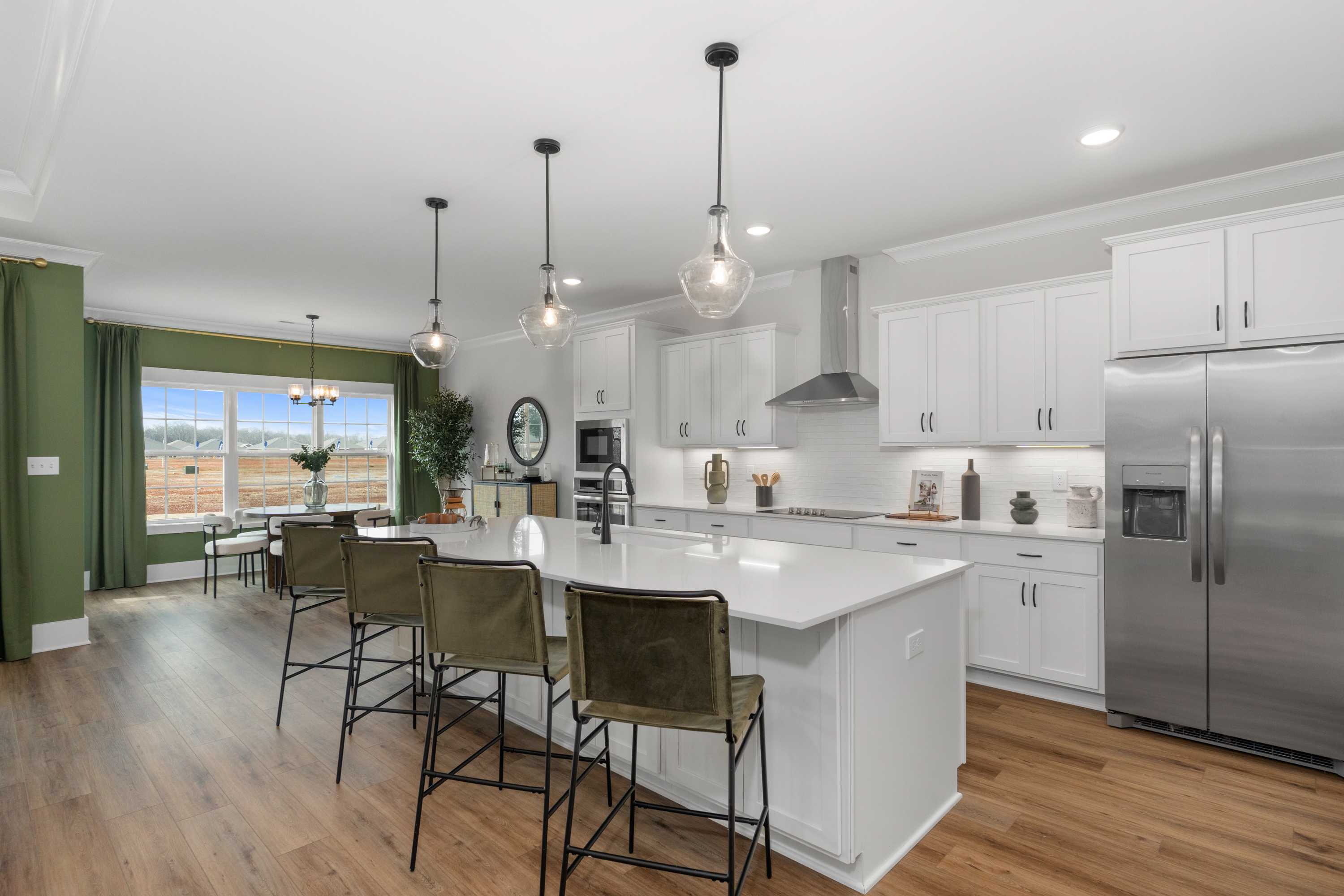 Spacious modern kitchen in Briercreek Meridianville AL by Davidson Homes with white quartz island, green accent wall, and hardwood floors