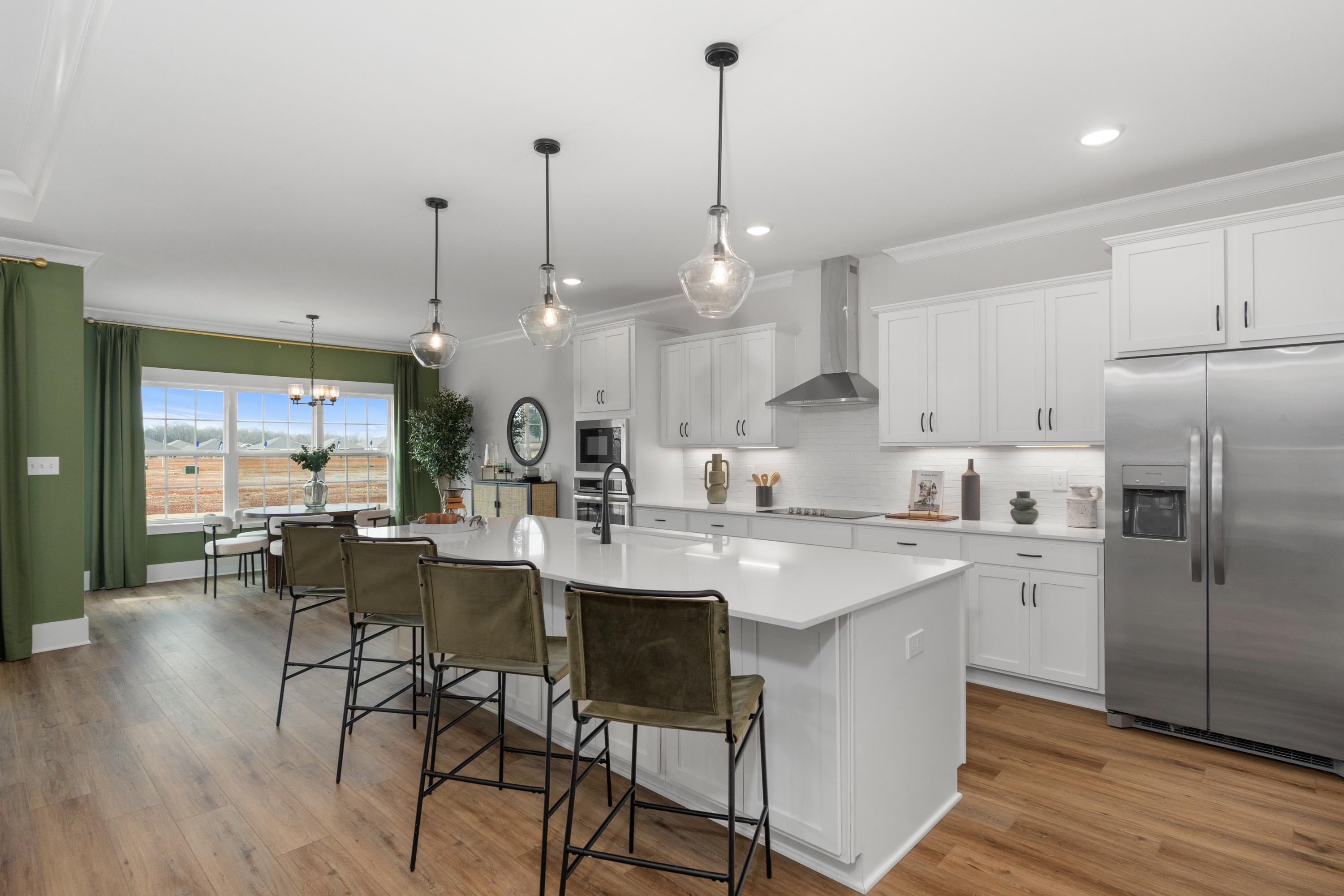 Spacious modern kitchen in Briercreek Meridianville AL by Davidson Homes with white quartz island, green accent wall, and hardwood floors