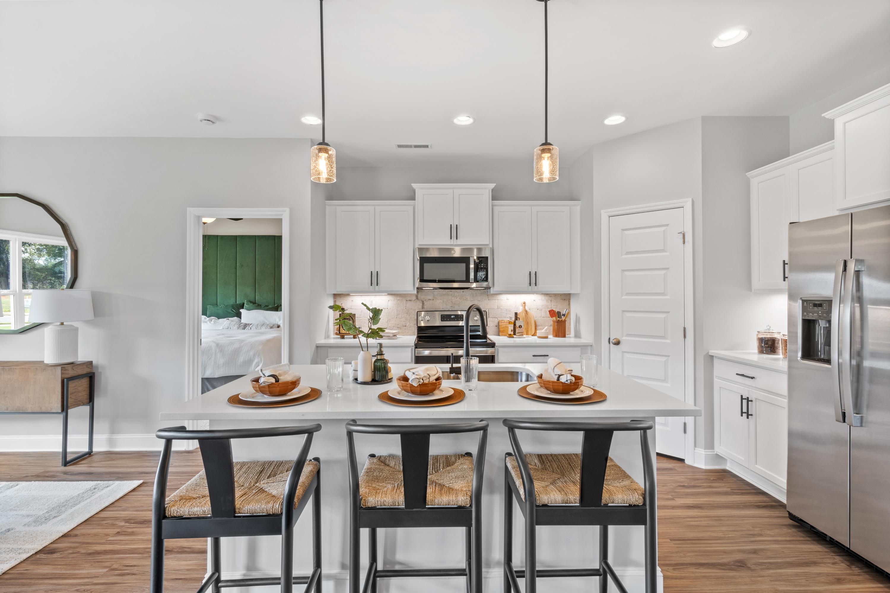 Bright modern kitchen in Wood Trail, Toney Alabama with white cabinets, large island, pendant lights and hardwood floors