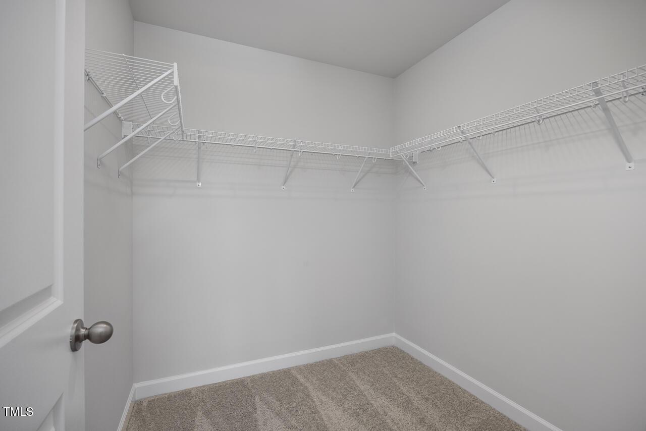Spacious walk-in closet with white wire shelving and carpeted floor in Davidson Homes The Warren Interior, Fuquay-Varina, NC