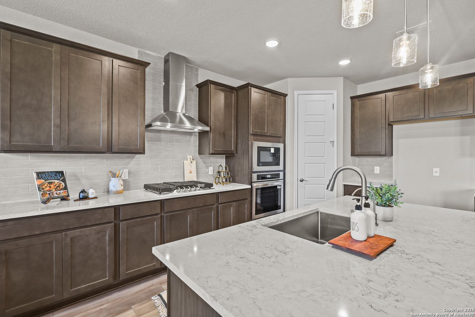 Modern kitchen with shaker cabinets, quartz countertops, stainless steel range and island sink in The Jennings G by Davidson Homes, Castroville TX