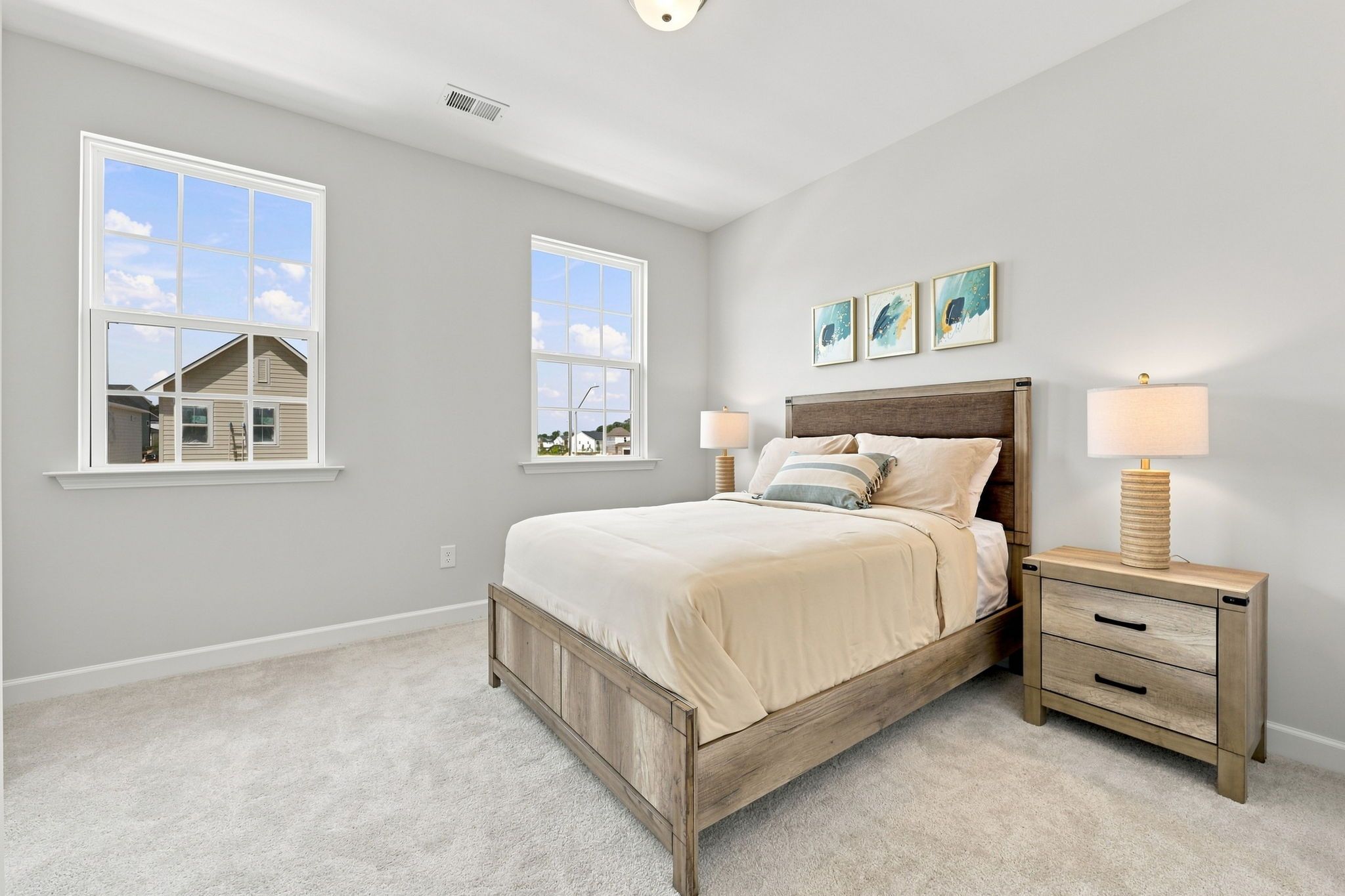 Spacious master bedroom in The Jordan A by Davidson Homes featuring neutral decor, wooden bed frame, and natural light.