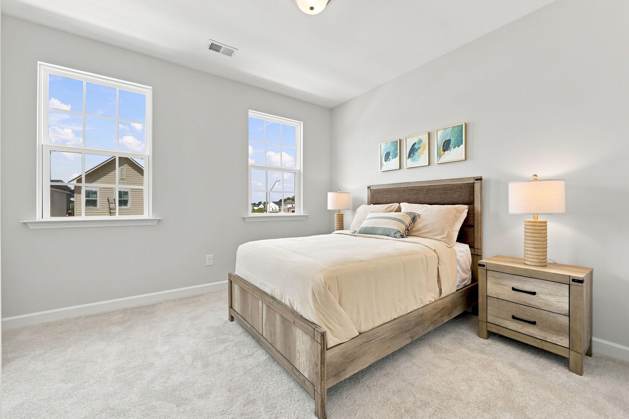 Spacious master bedroom in The Jordan A by Davidson Homes featuring neutral decor, wooden bed frame, and natural light.