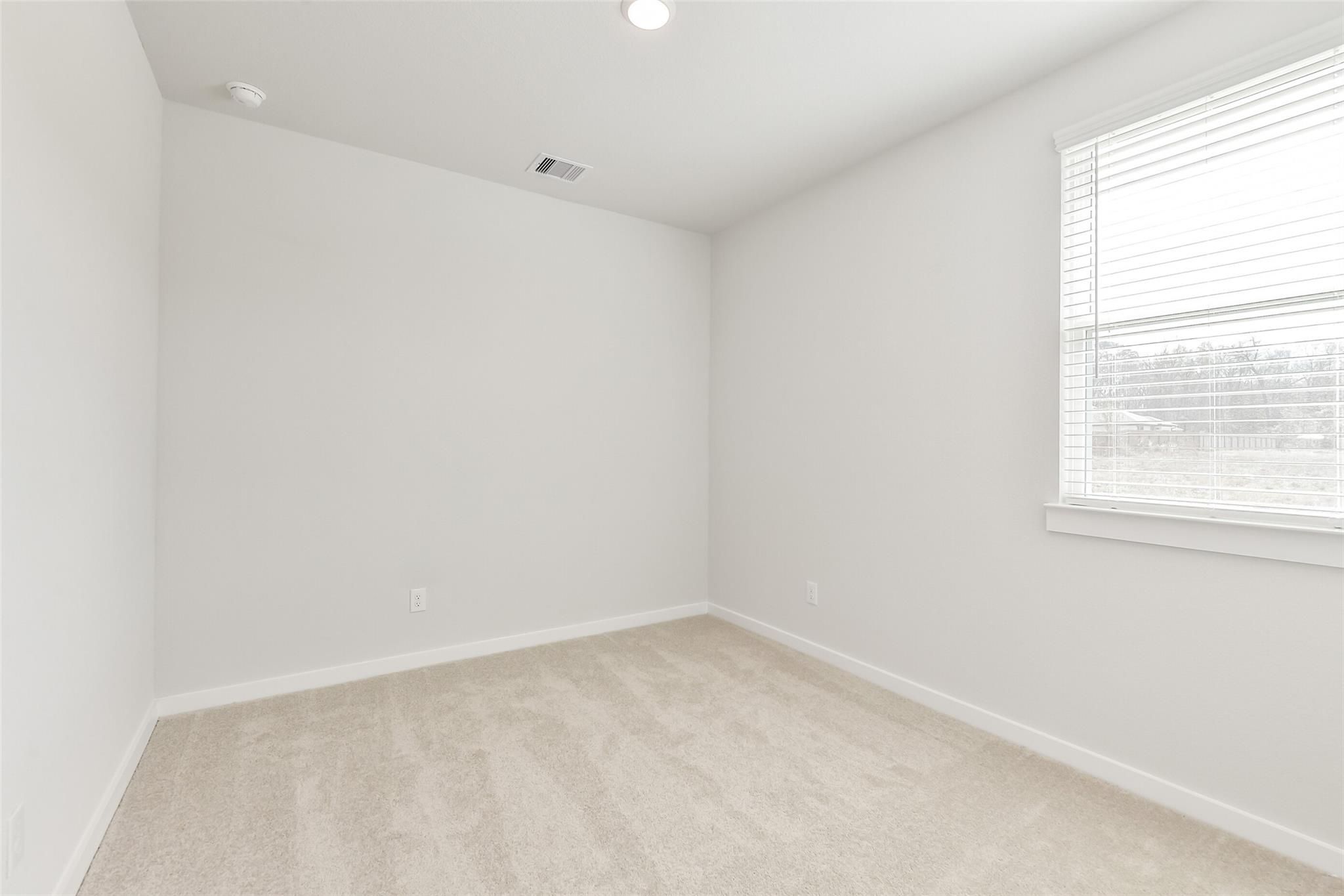 Spacious, sunlit bedroom with neutral carpet in The Colorado F floor plan by Davidson Homes in Liberty Estates, Texas.