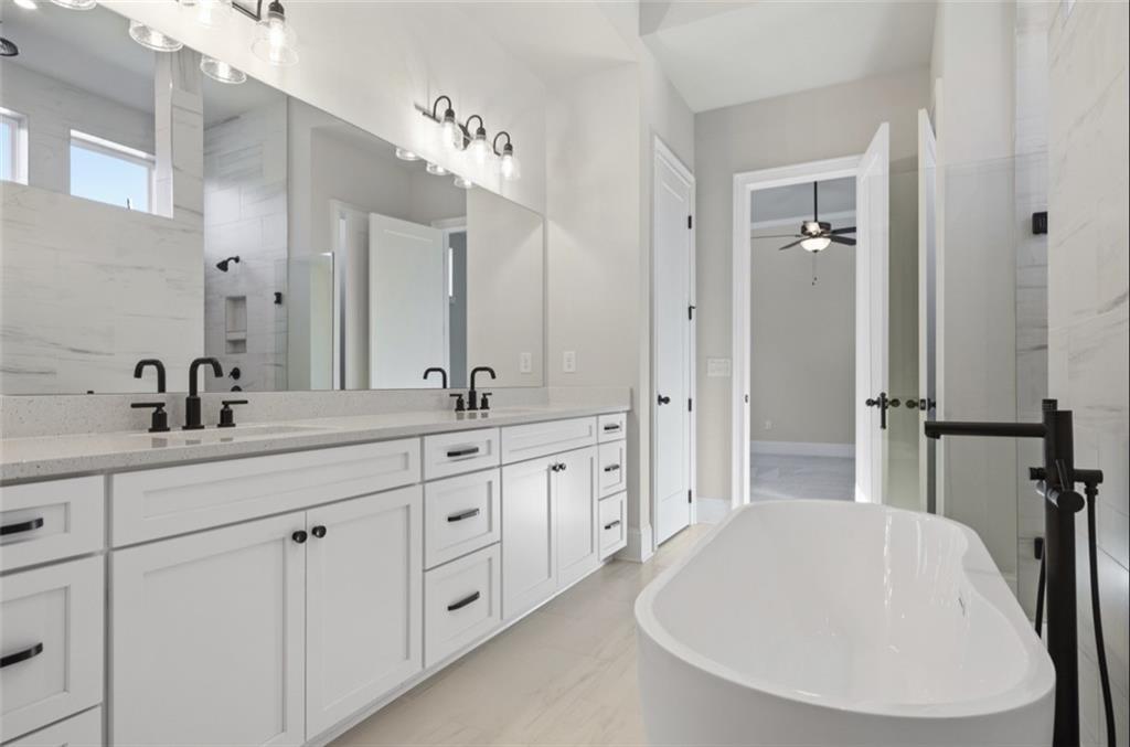 Elegant master bathroom with white double vanity, freestanding tub, and walk-in shower in Davidson Homes The Seaside A, Woodstock, GA