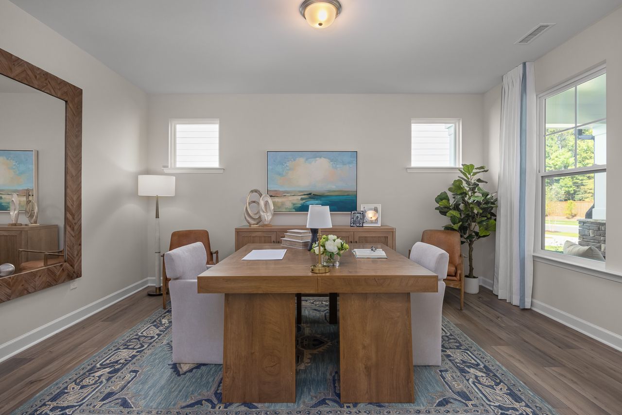 Modern home office at Sage on North Main in Wake Forest, NC with wood desk, area rug, and large floor mirror.