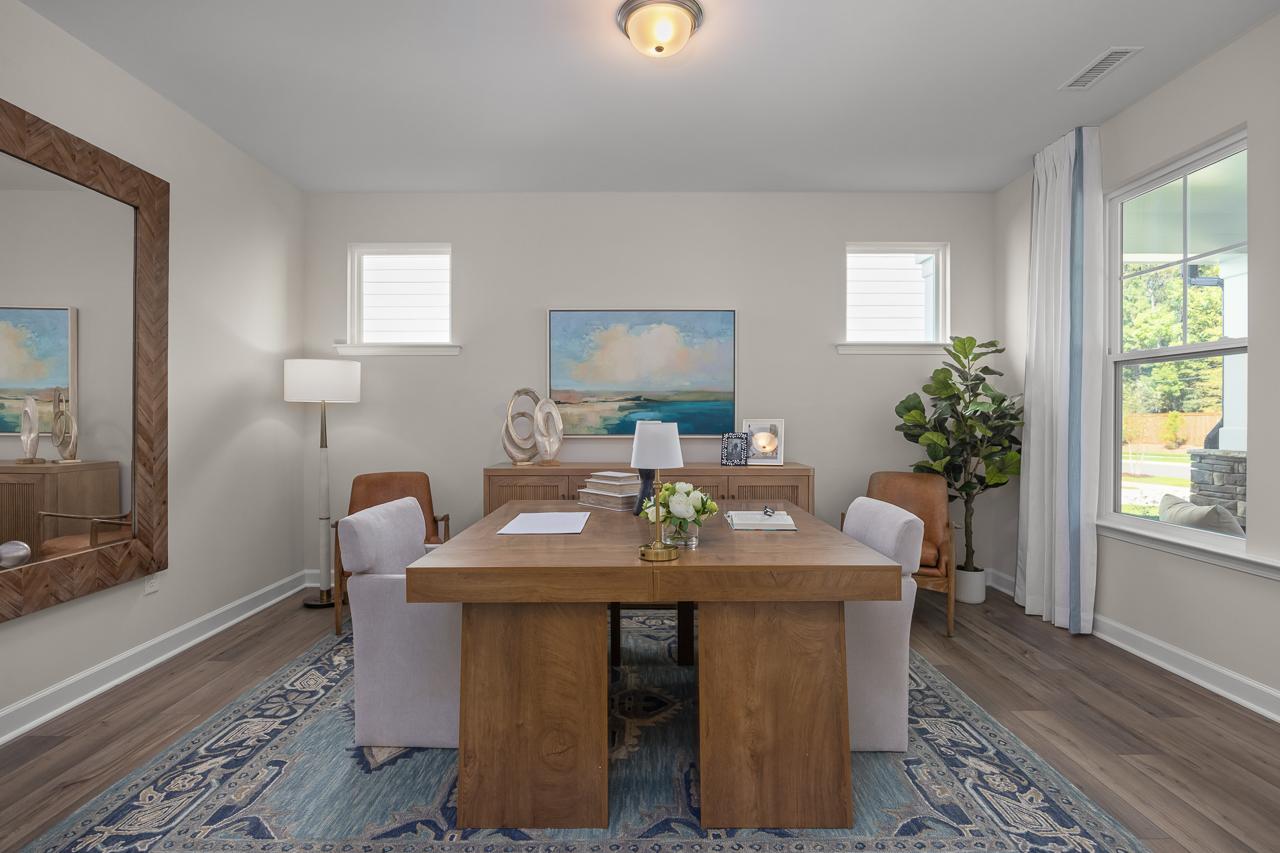 Modern home office at Sage on North Main in Wake Forest, NC with wood desk, area rug, and large floor mirror.