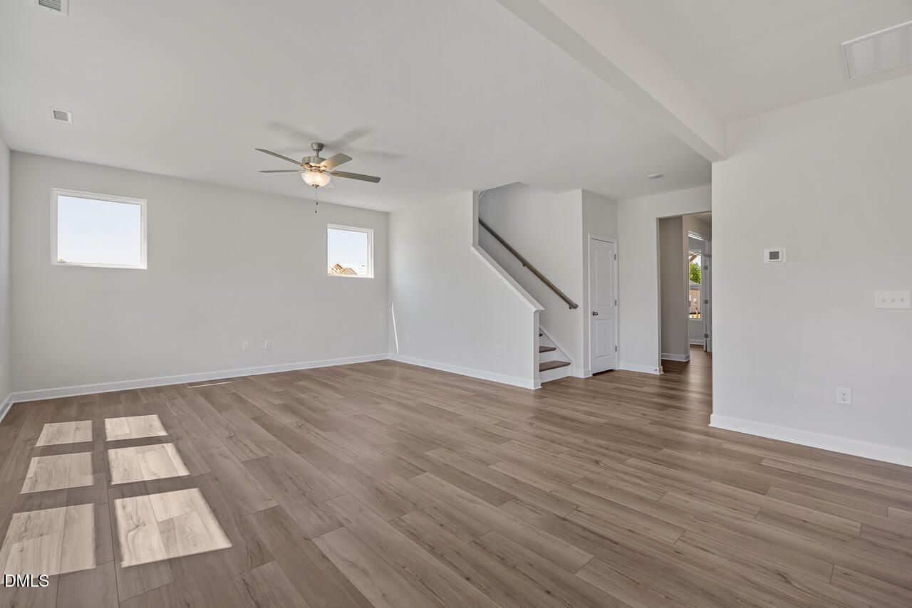 Bright open-concept living area with wood-style flooring in The Chestnut B floor plan at Retreat at North Main, Lillington.