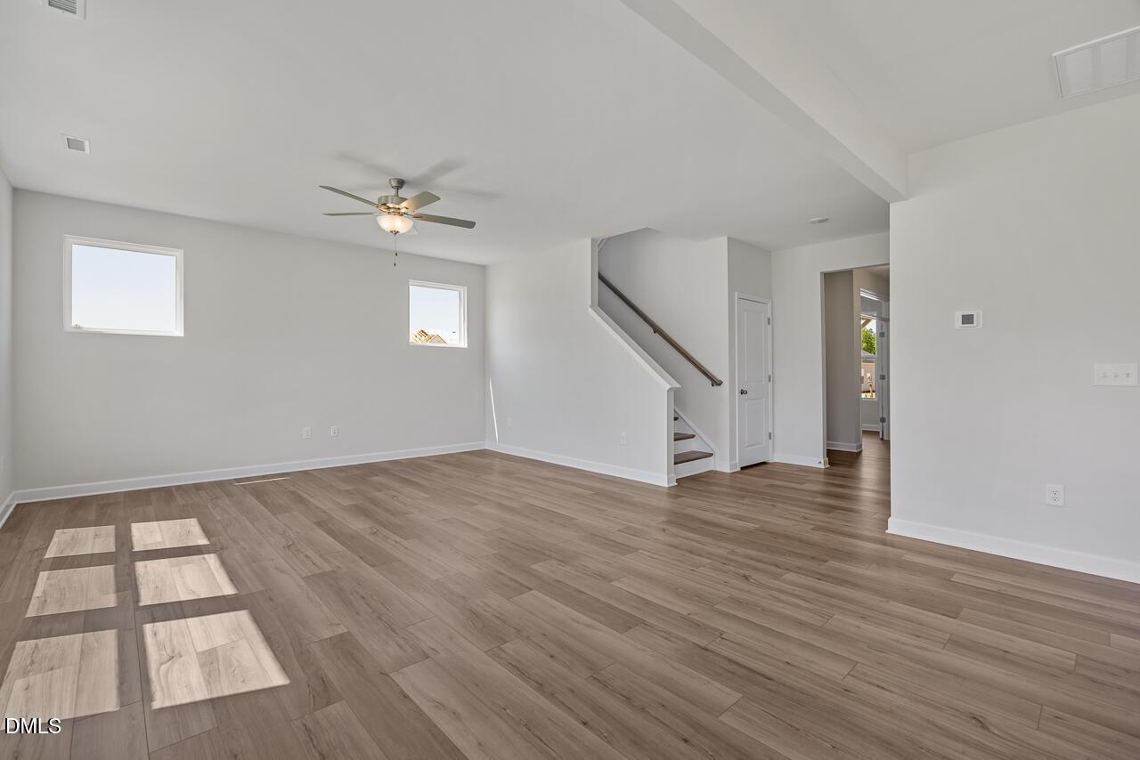 Spacious open-concept living area with wood-style flooring in The Chestnut B floor plan at Retreat at North Main, Lillington.