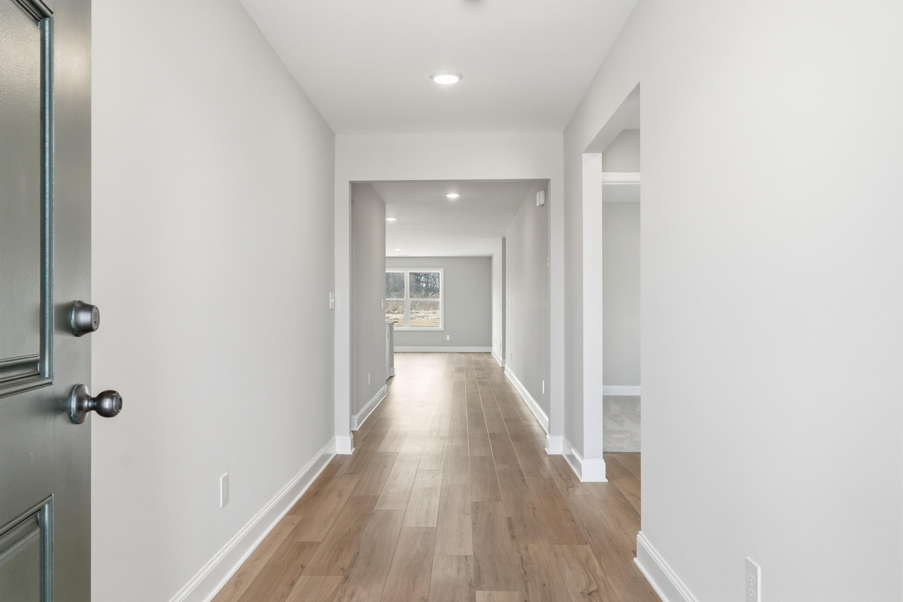 Spacious entry hallway in The Daphne V home featuring light wood floors, white walls, and open archways