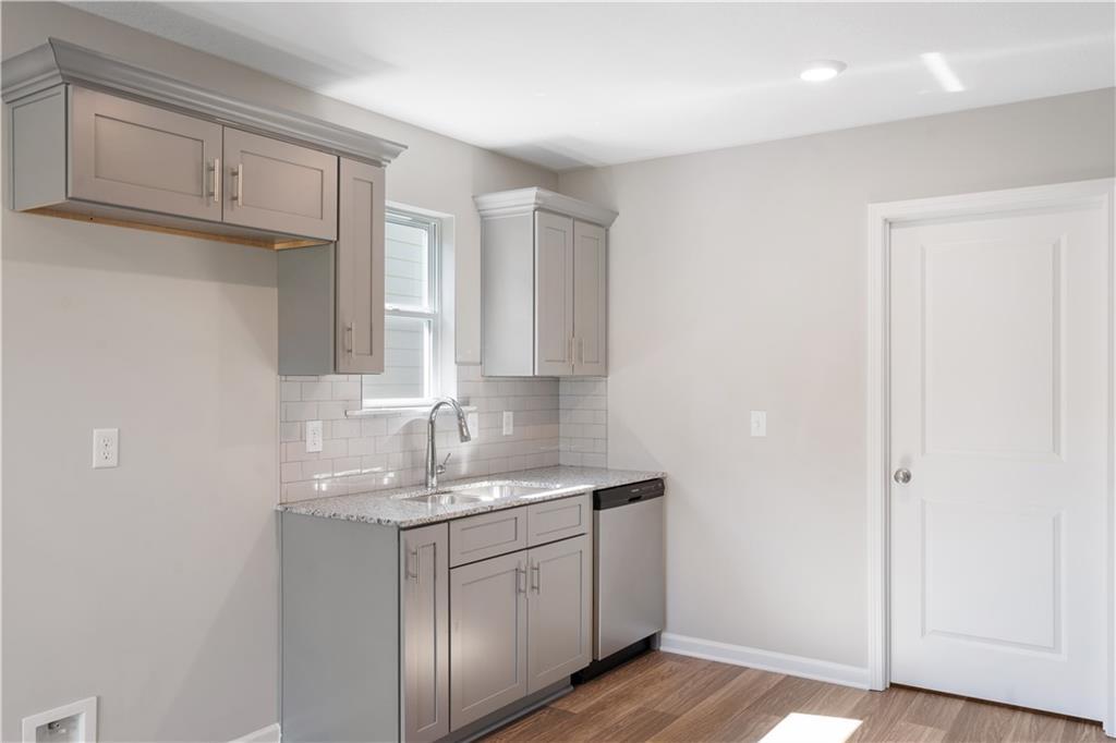 Modern kitchen with gray shaker cabinets, white subway tile backsplash, stainless dishwasher in Davidson Homes The Washington, Phenix City