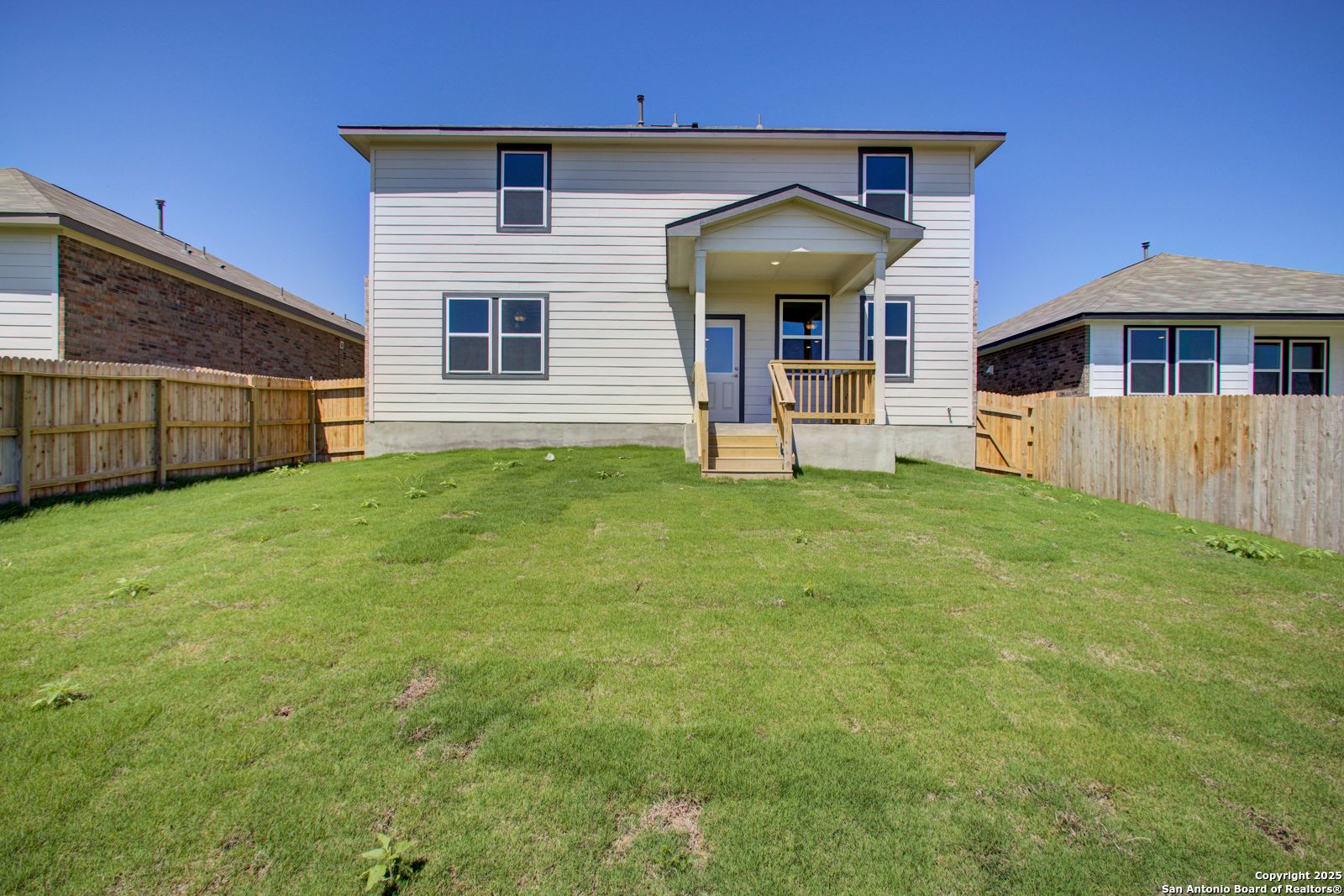 Two-story white home with covered back patio, large green backyard, and wood fences in Comanche Ridge, San Antonio, Texas - Davidson Homes The Douglas G