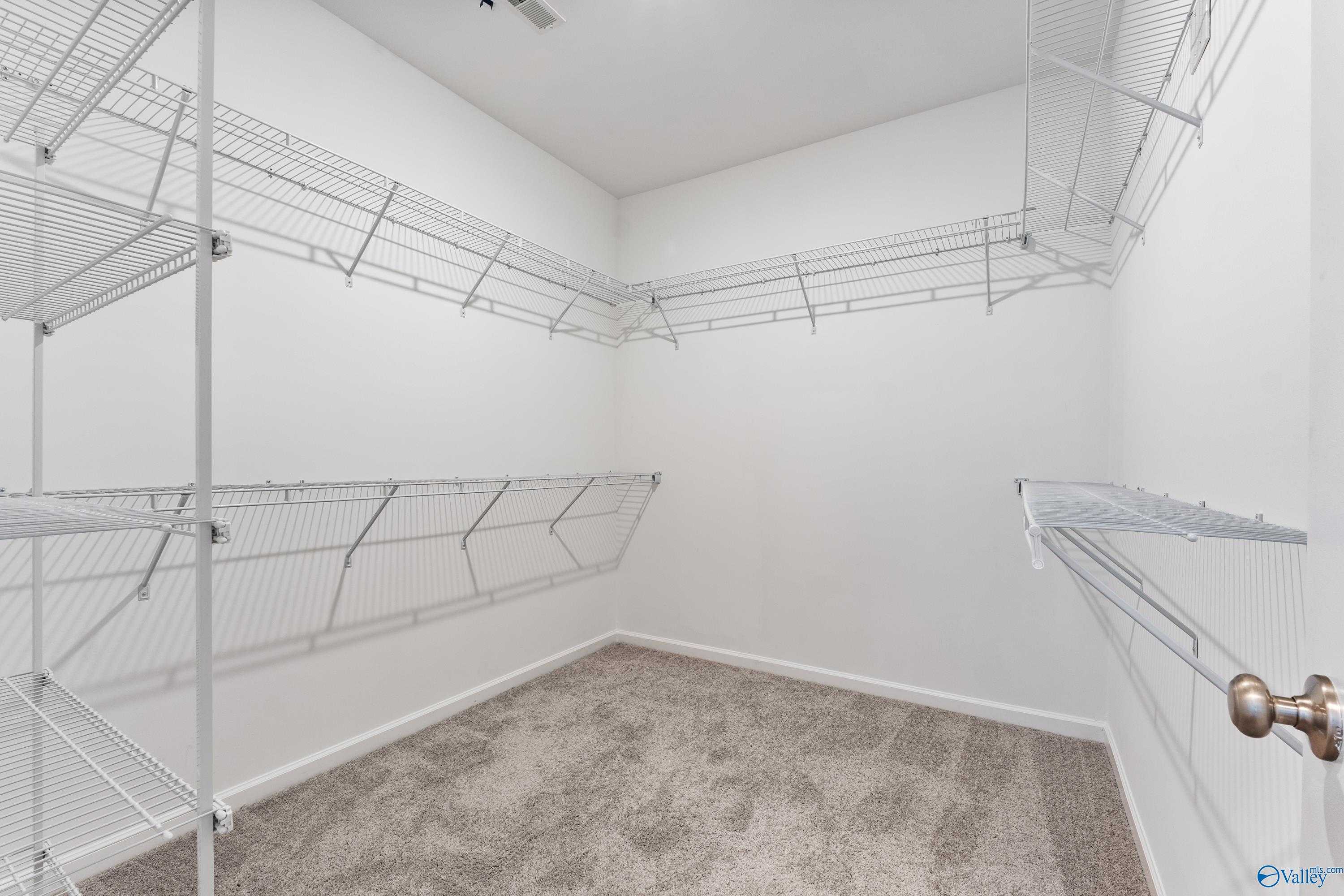 Spacious walk-in closet with white wire shelving and carpeted floor in Davidson Homes The Sanctuary, Riverton Preserve, Huntsville, Alabama