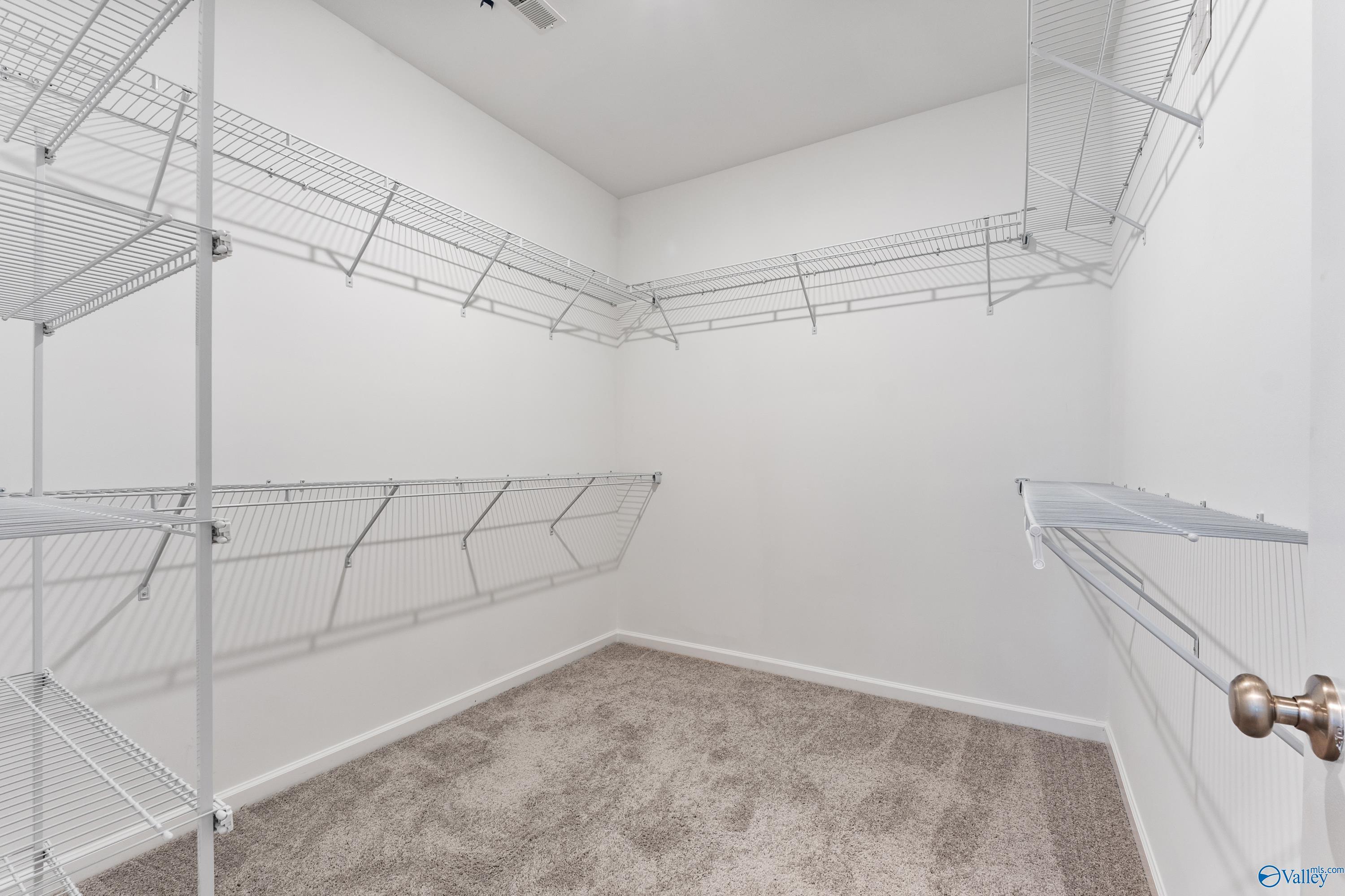 Spacious walk-in closet with white wire shelving and carpeted floor in Davidson Homes The Sanctuary, Huntsville, Alabama