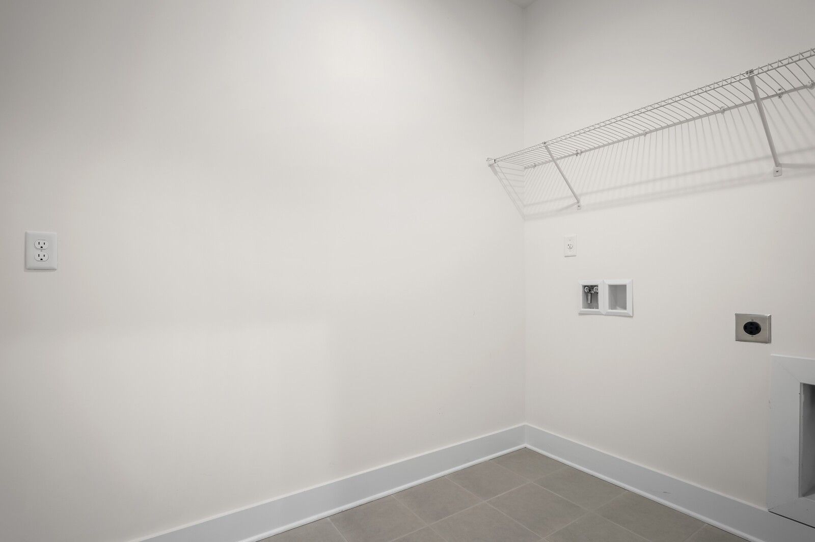 Laundry room with wire shelving and utility hookups in The Ash A floor plan at Woods Crossing, Gallatin, Tennessee.