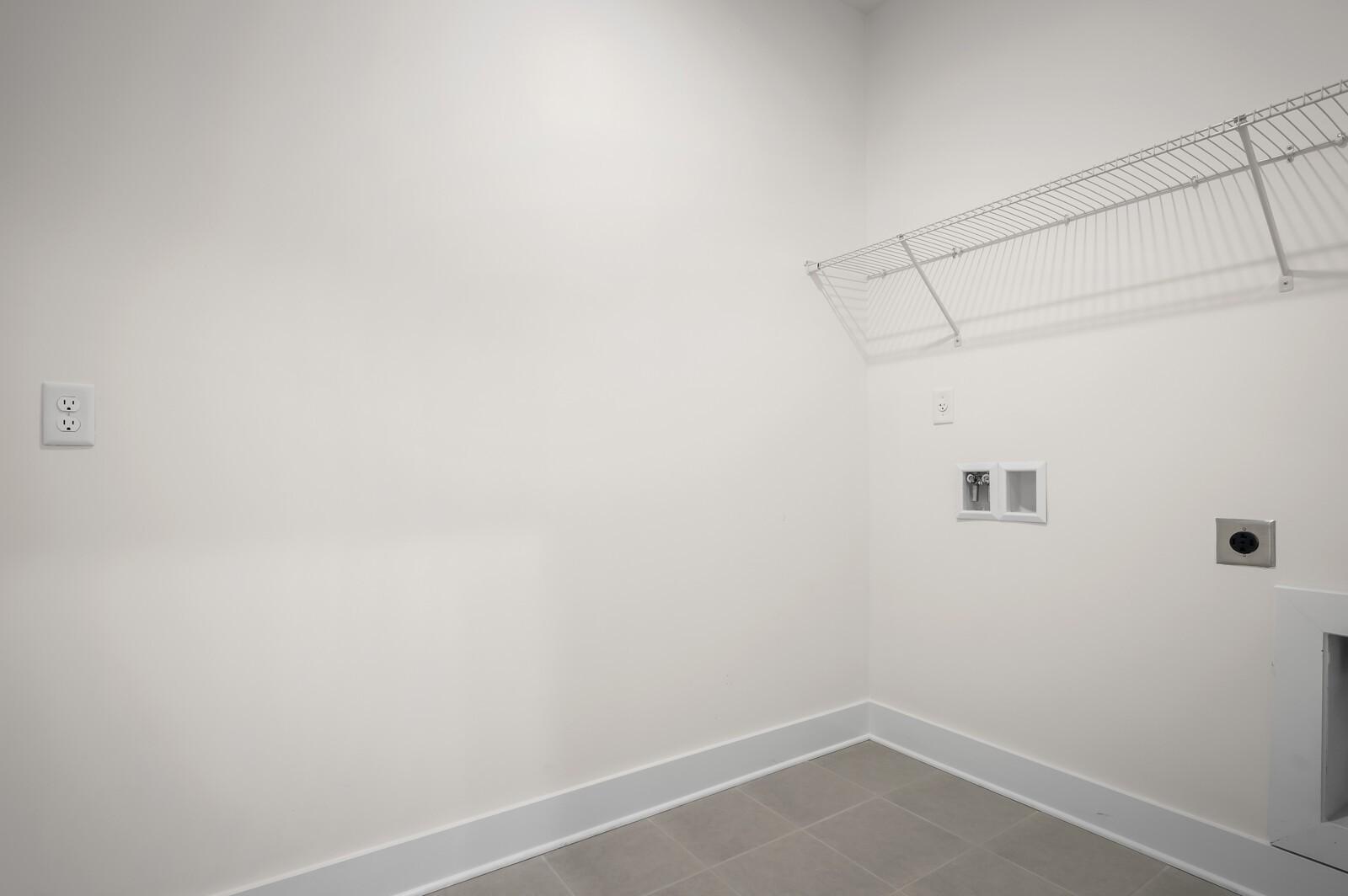 Laundry room with wire shelving and utility hookups in The Ash A floor plan at Woods Crossing, Gallatin, Tennessee.