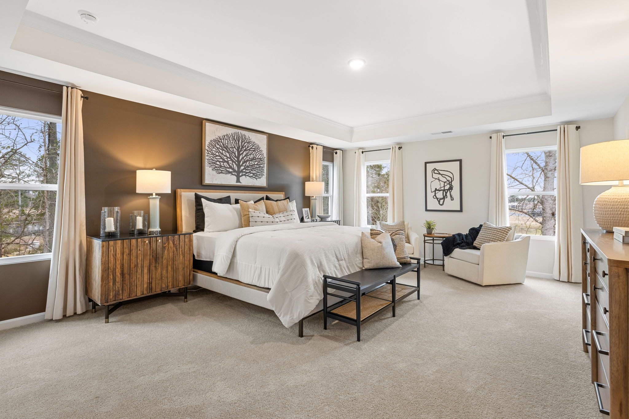 Spacious master bedroom at Lake Shore in Winder GA with king bed, neutral tones, abstract art, and large tree-view windows