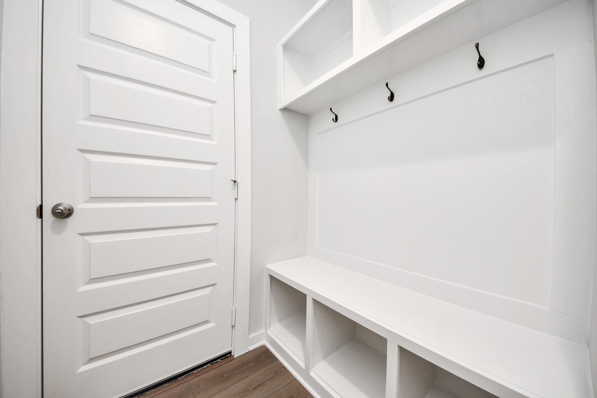 White mudroom bench with storage cubbies and coat hooks in The Riviera A floor plan at Emberly, Beasley, Texas.