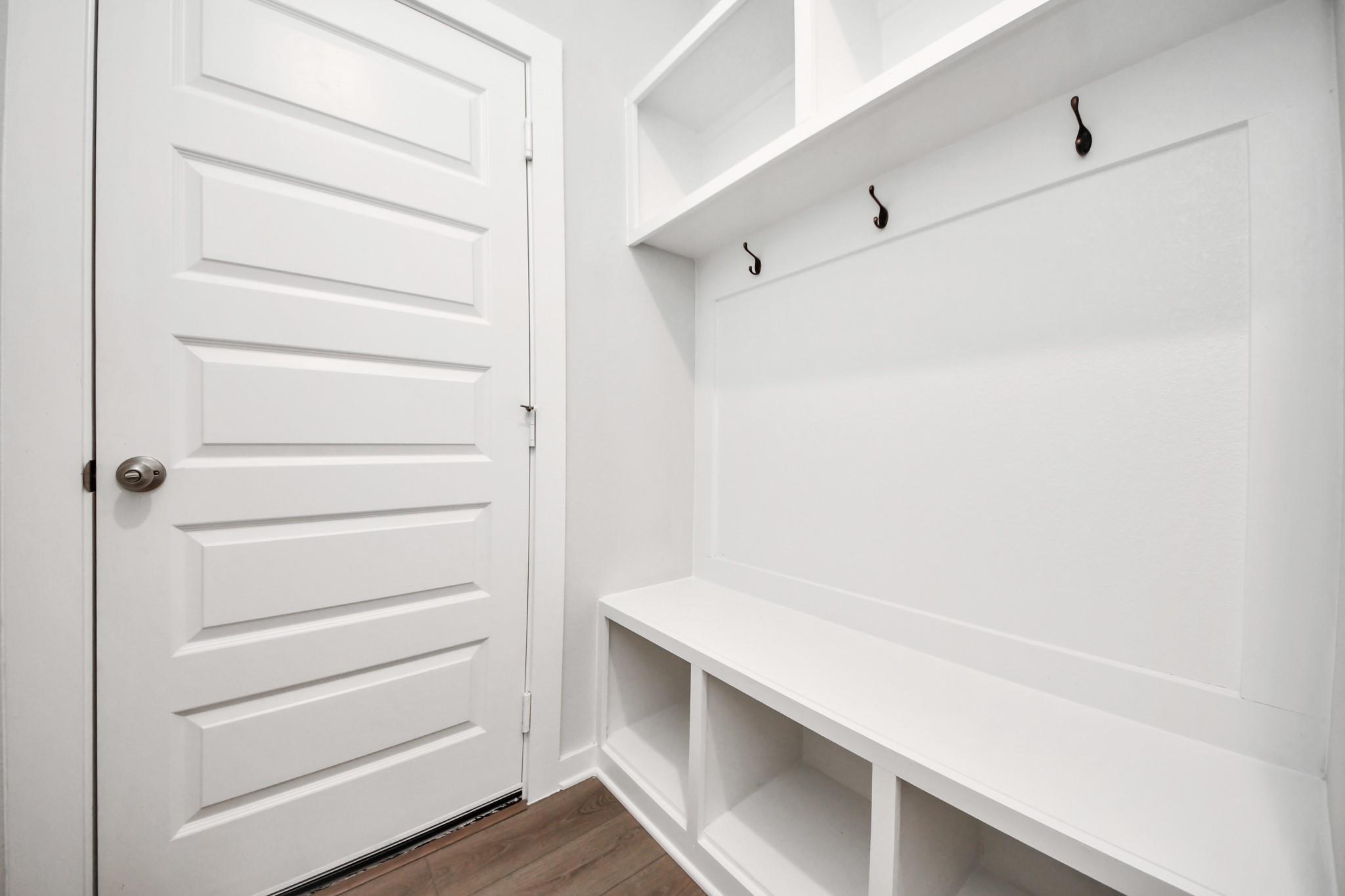 White mudroom bench with storage cubbies and coat hooks in The Riviera A floor plan at Emberly, Beasley, Texas.