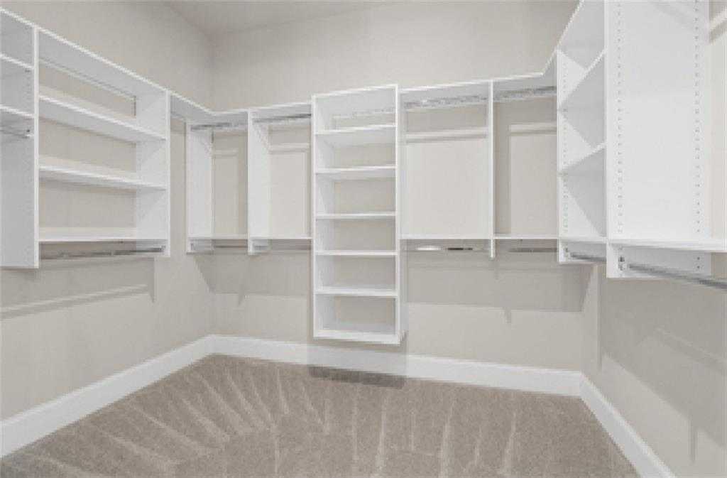 Spacious walk-in closet with white built-in shelving and rods in Davidson Homes The Seaside A, Woodstock, Georgia