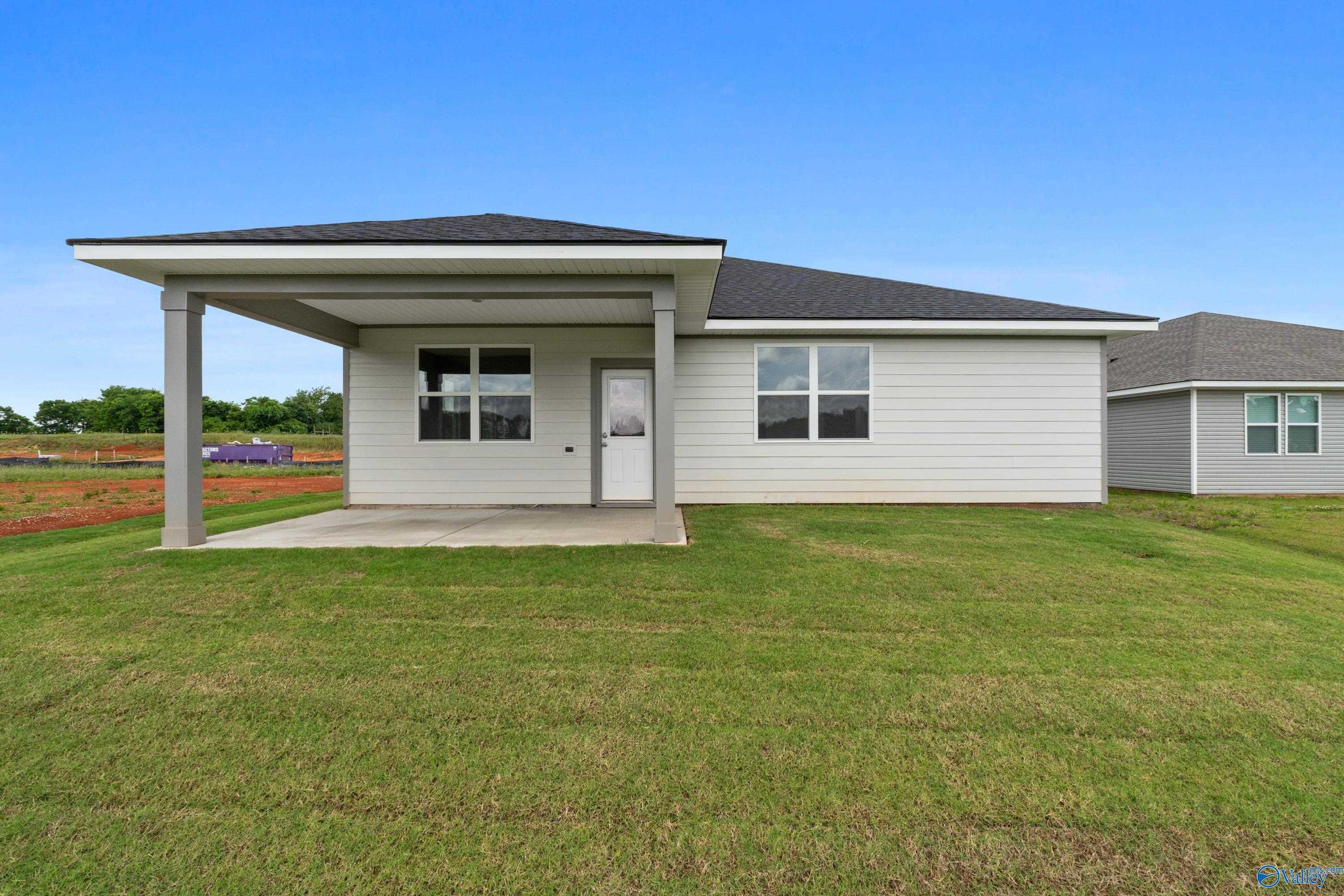 Rear view of The Aurora 4-bedroom home by Evermore Homes with covered patio and green lawn in Carroll Green, Harvest, Alabama