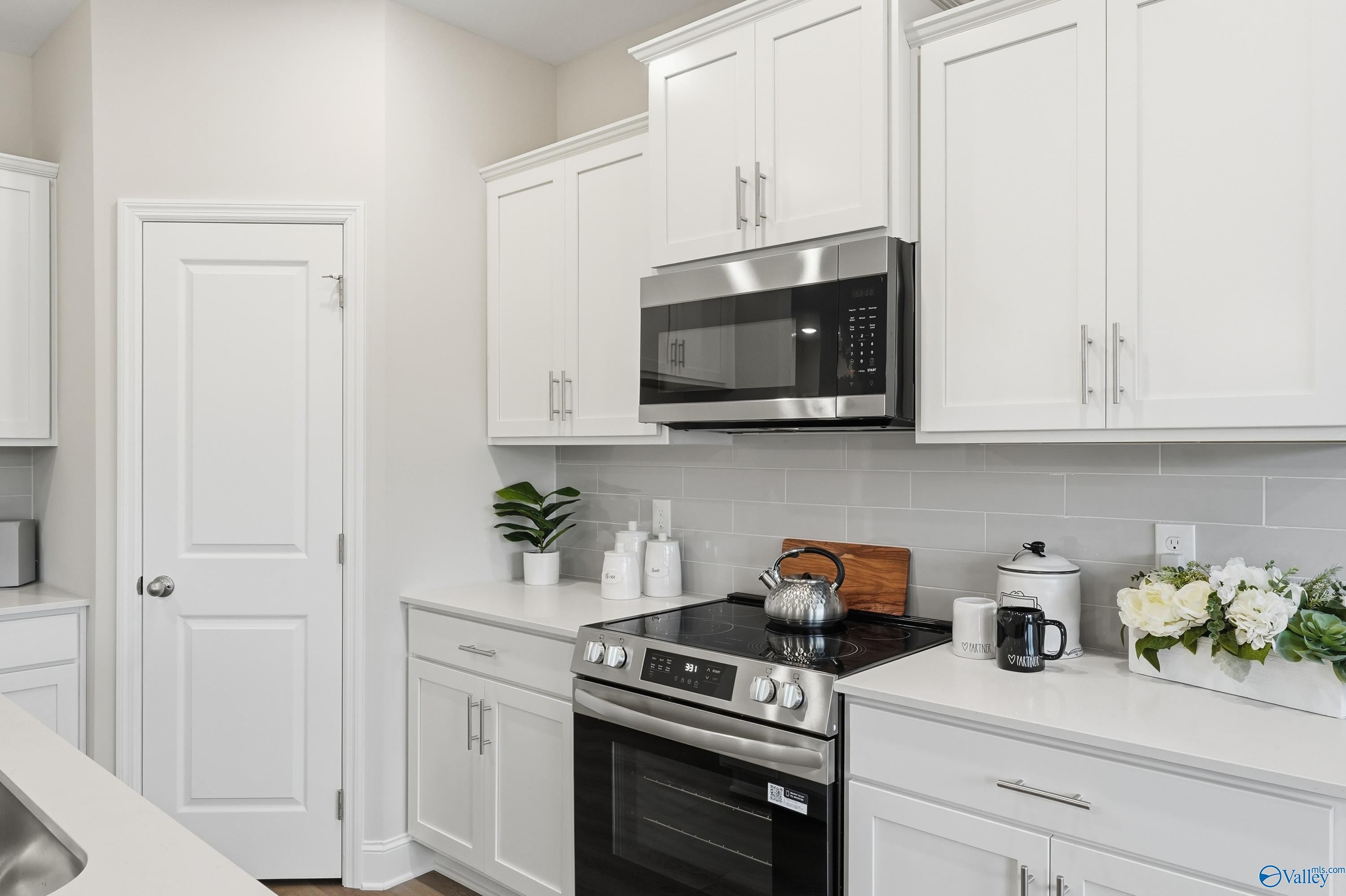 Modern white kitchen featuring stainless steel appliances, subway tile backsplash in Davidson Homes The Asheville, Toney, AL