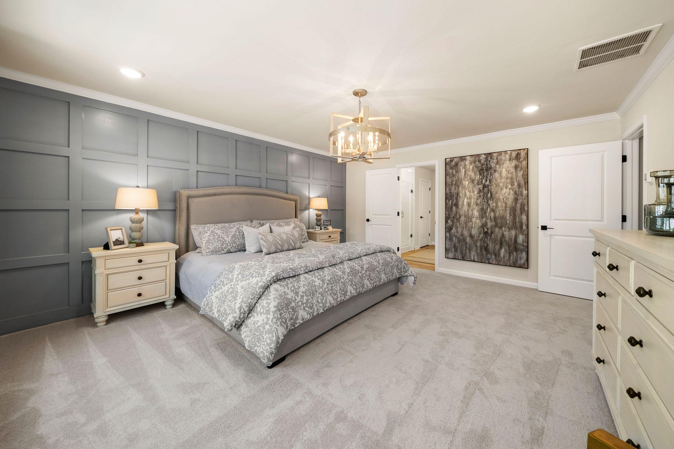 Primary bedroom in Riverwood Dallas GA by Davidson Homes with gray shiplap accent wall king bed and chandelier