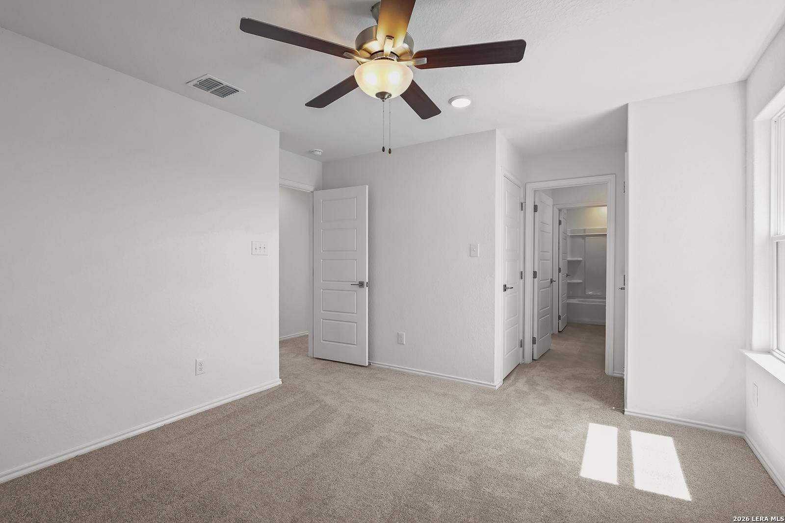 Spacious bedroom with ceiling fan, double closet doors, and en-suite bathroom in Davidson Homes Sequoia B, San Antonio, Texas